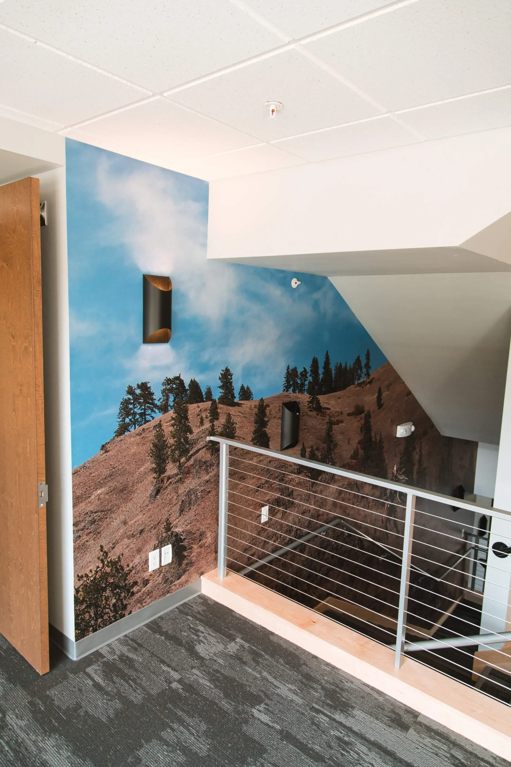 Interior stairwell wall wrap featuring blue sky and mountain ridge by Wrap Agency for Location: MeatEater, Bozeman, MT.