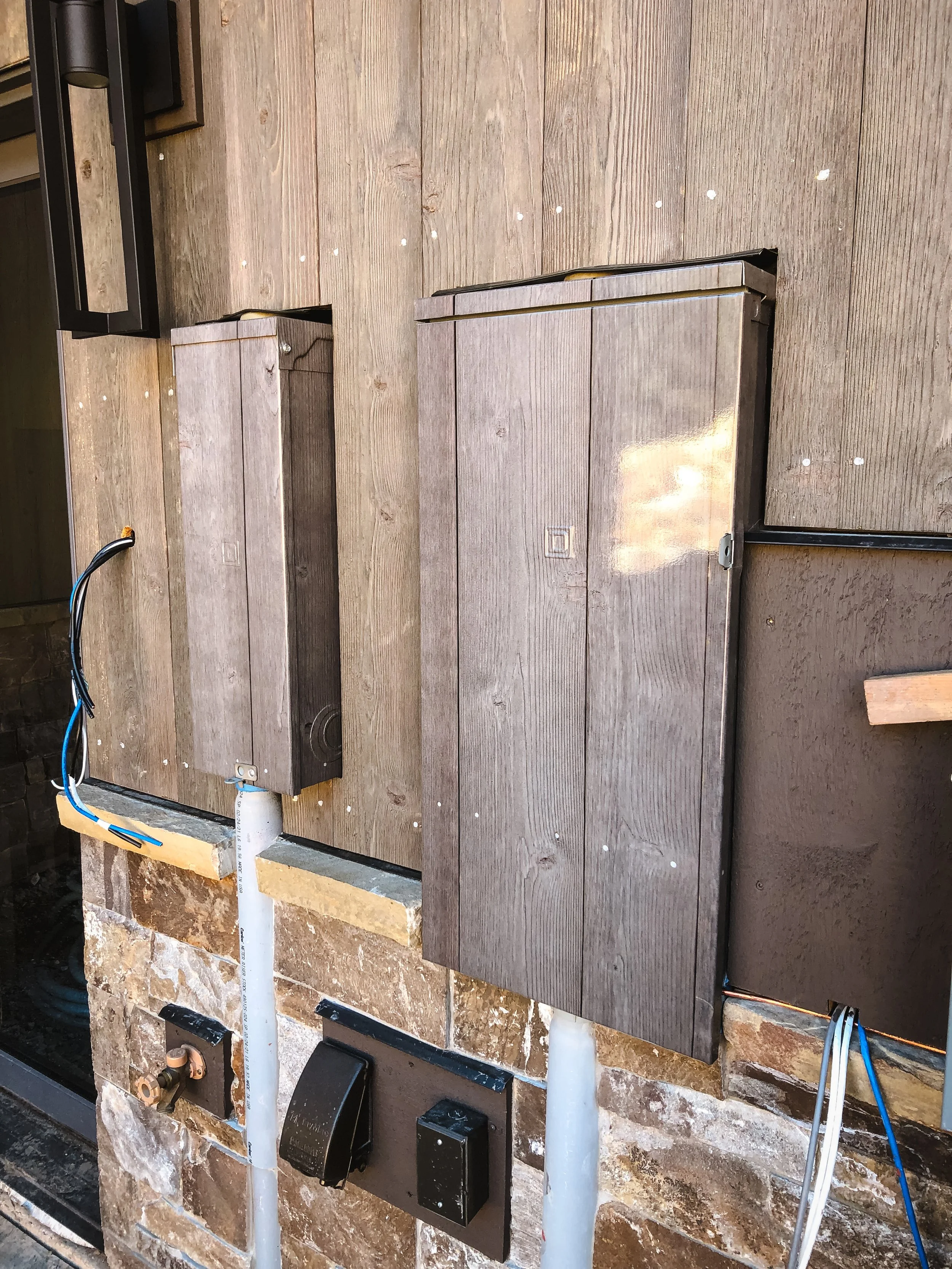 Vinyl wrap utility box designed to mimic aged wooden paneling and exposed pipes.