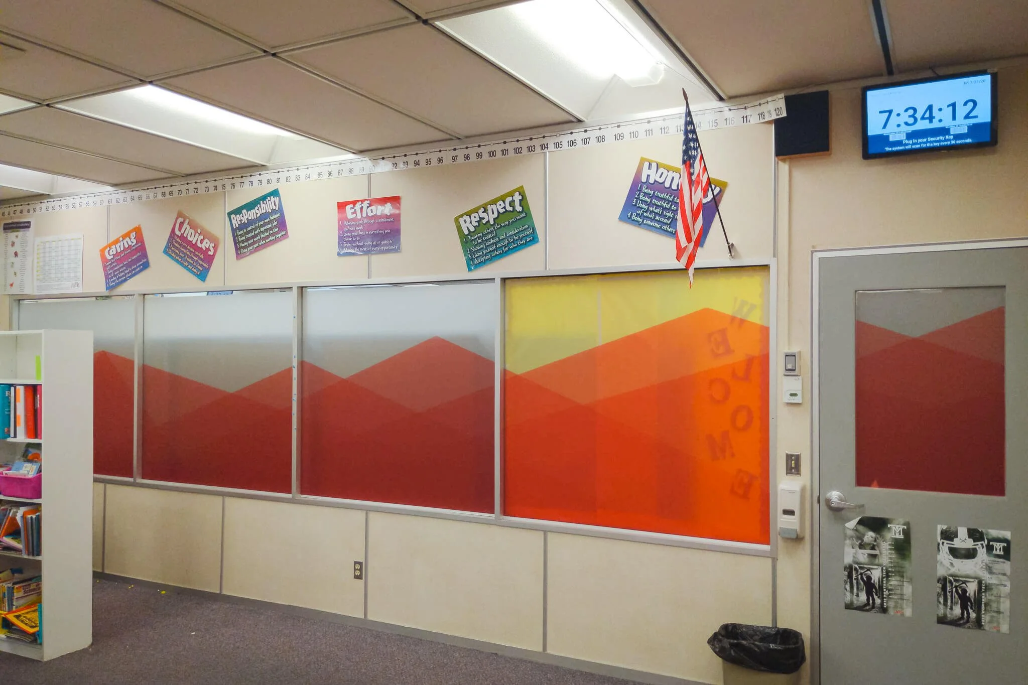 A classroom interior with large interior windows and doors covered in cohesive red and orange geometric window graphics, used as privacy window film across multiple glass panels.
