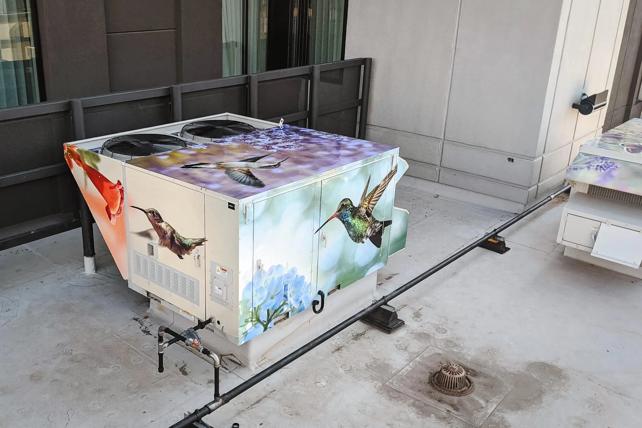 Rooftop air conditioning unit vinyl wrap with multiple photographs of hovering hummingbirds drinking out of flowers