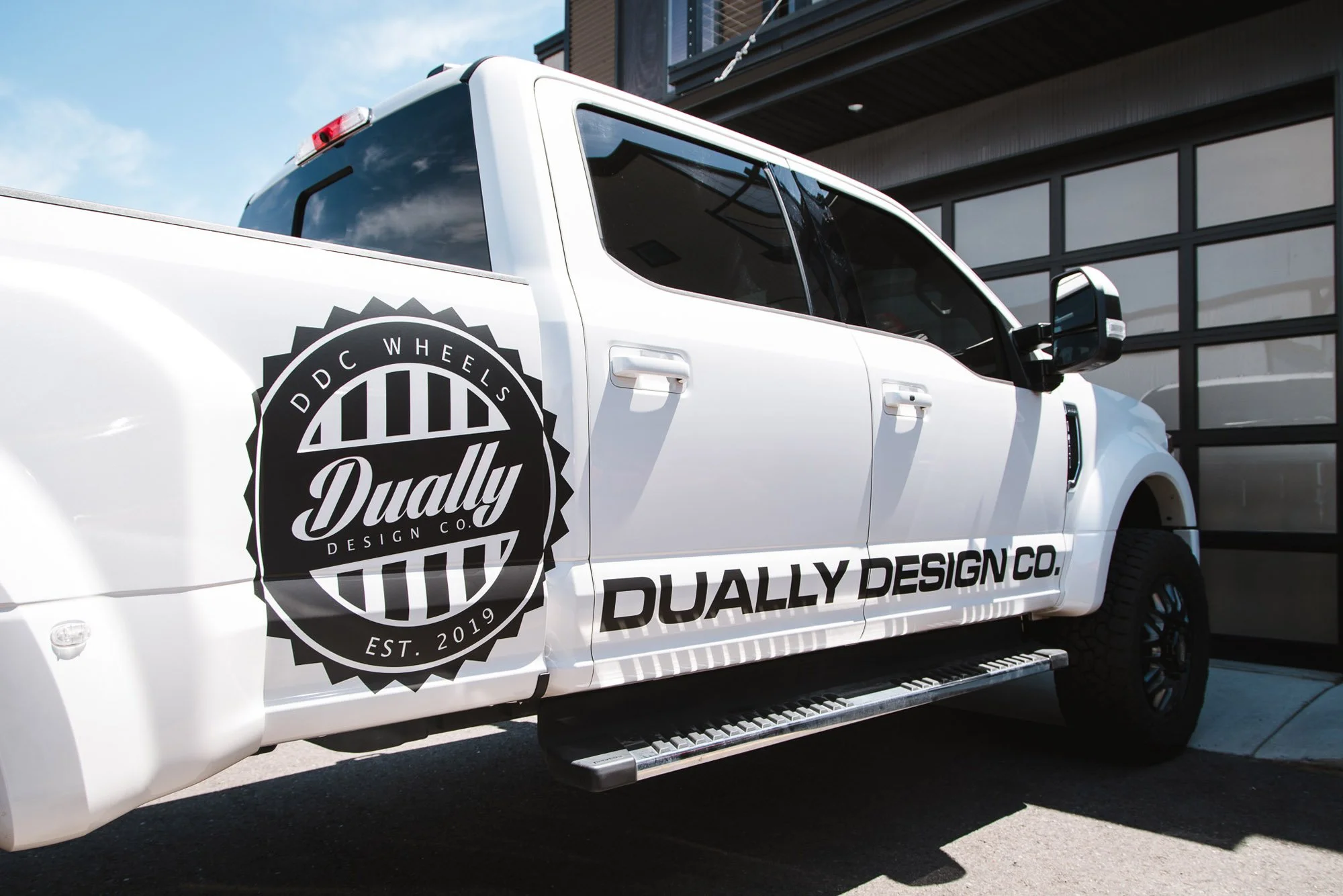 White truck featuring bold circular logo and minimalist black text for Dually Design Co., showcasing a clean, high-impact vinyl vehicle wrap with custom branding in Bozeman, Montana.