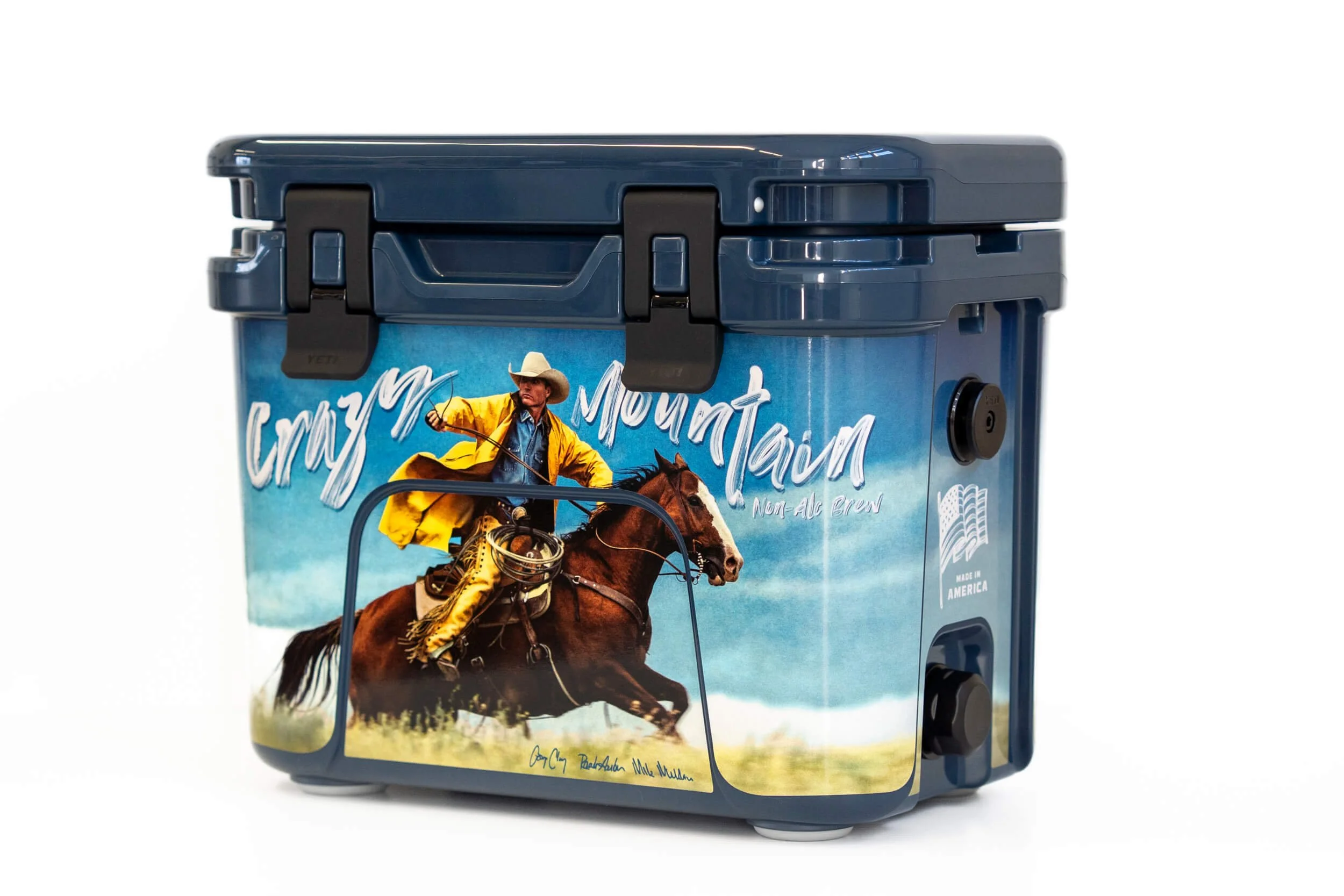 Front of a YETI Roadie cooler with a cowboy riding a horse with a moody blue sky background. Crazy Mountain text arched above