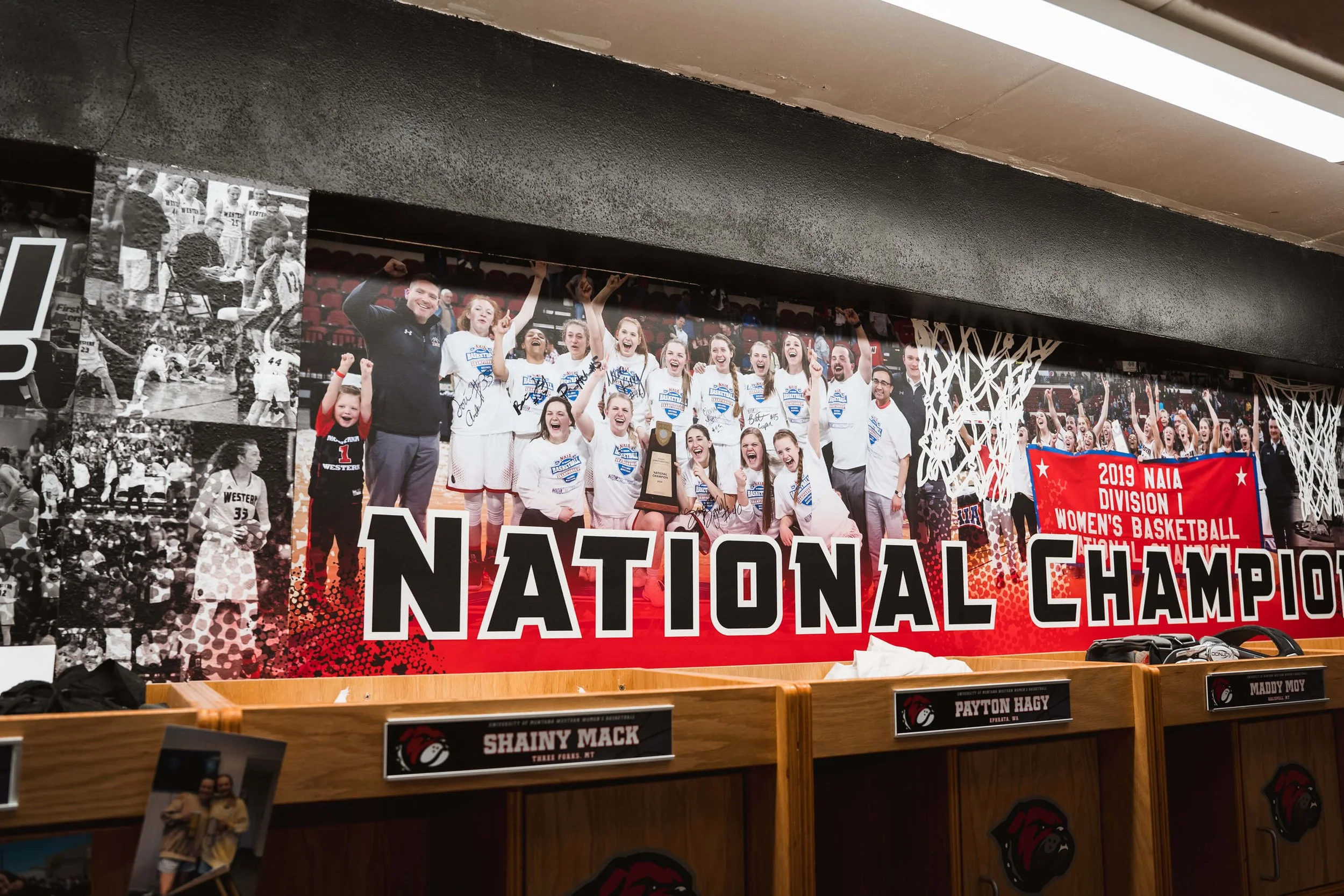 Collage-style red and black sports wall wrap for a locker room, featuring an action-packed photo collage of basketball players and the phrase “National Champions.” Business Location: UM Western in Dillon, MT. 