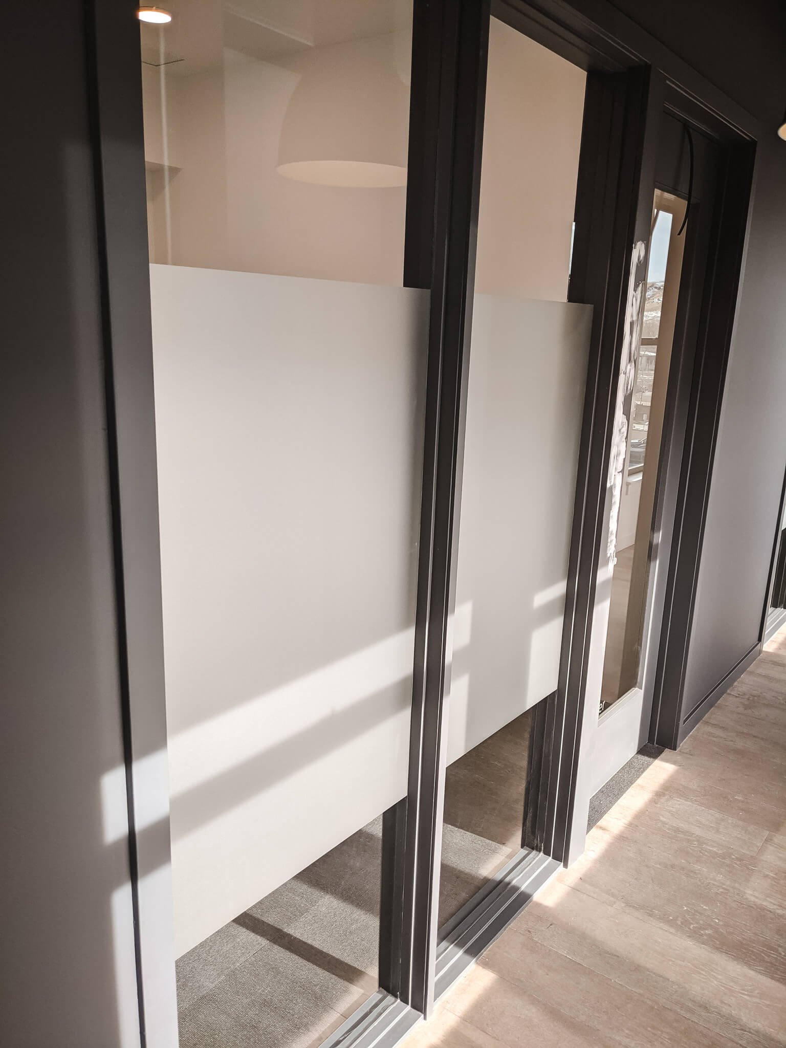 Horizontal banded window graphics applied to office glass partitions for semi-privacy, maintaining an open layout while providing subtle separation.