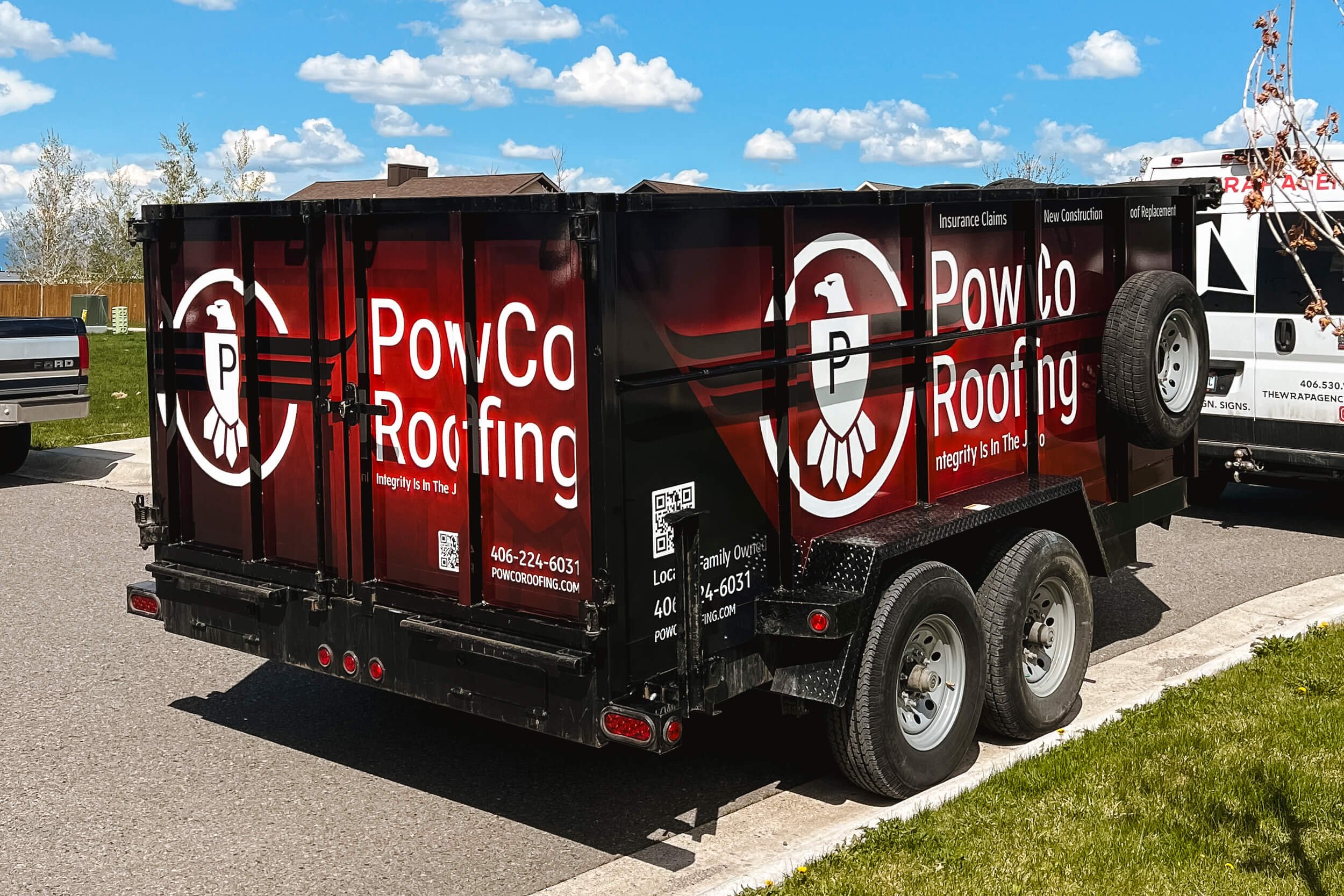 Angled rear view of a full wrap on a dump trailer with a red and black grunge background with neon logos overlaid