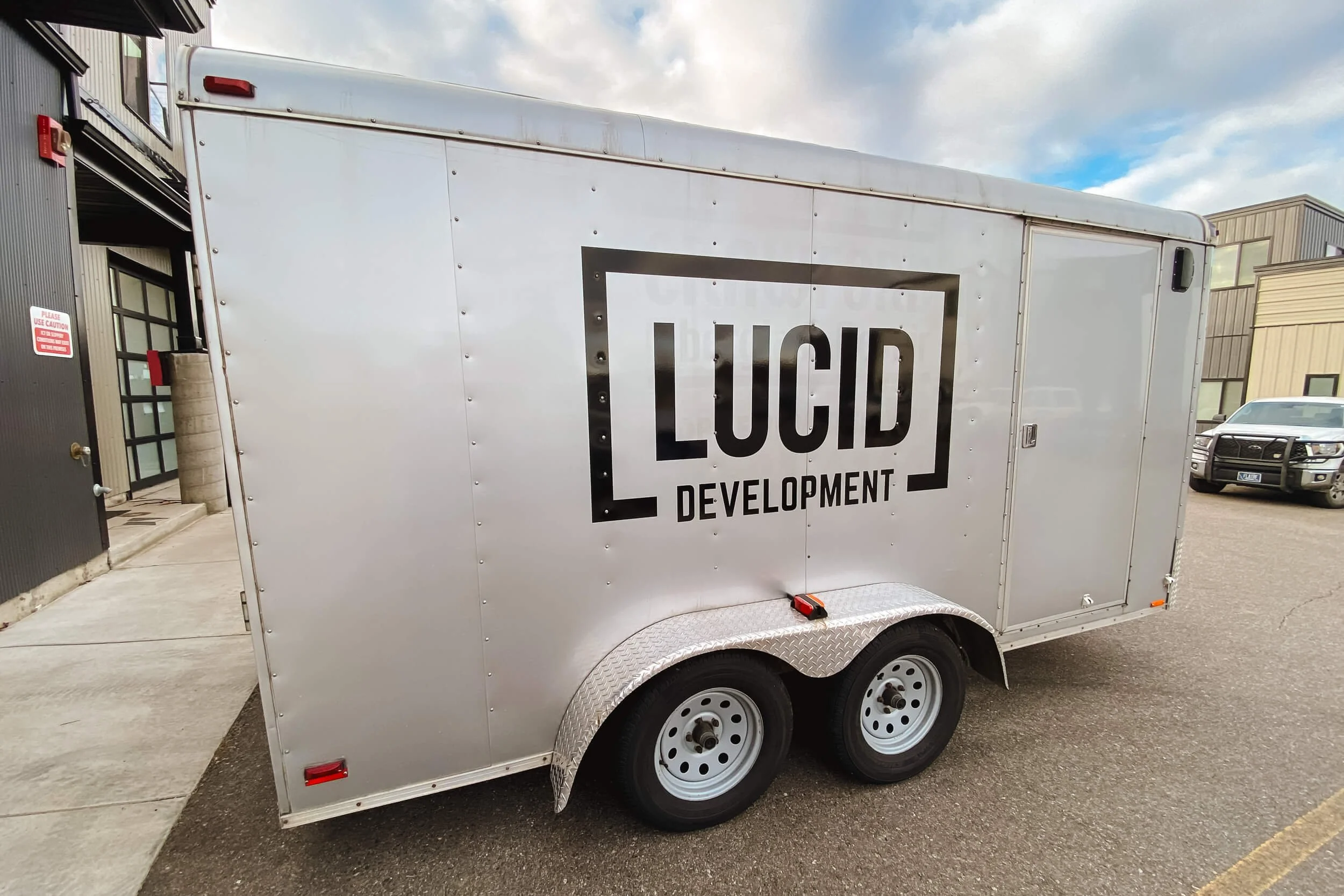 Silver trailer with minimalistic black Lucid Development trailer graphics in Bozeman, Montana, showcasing a clean logo-centered design ideal for construction branding.
