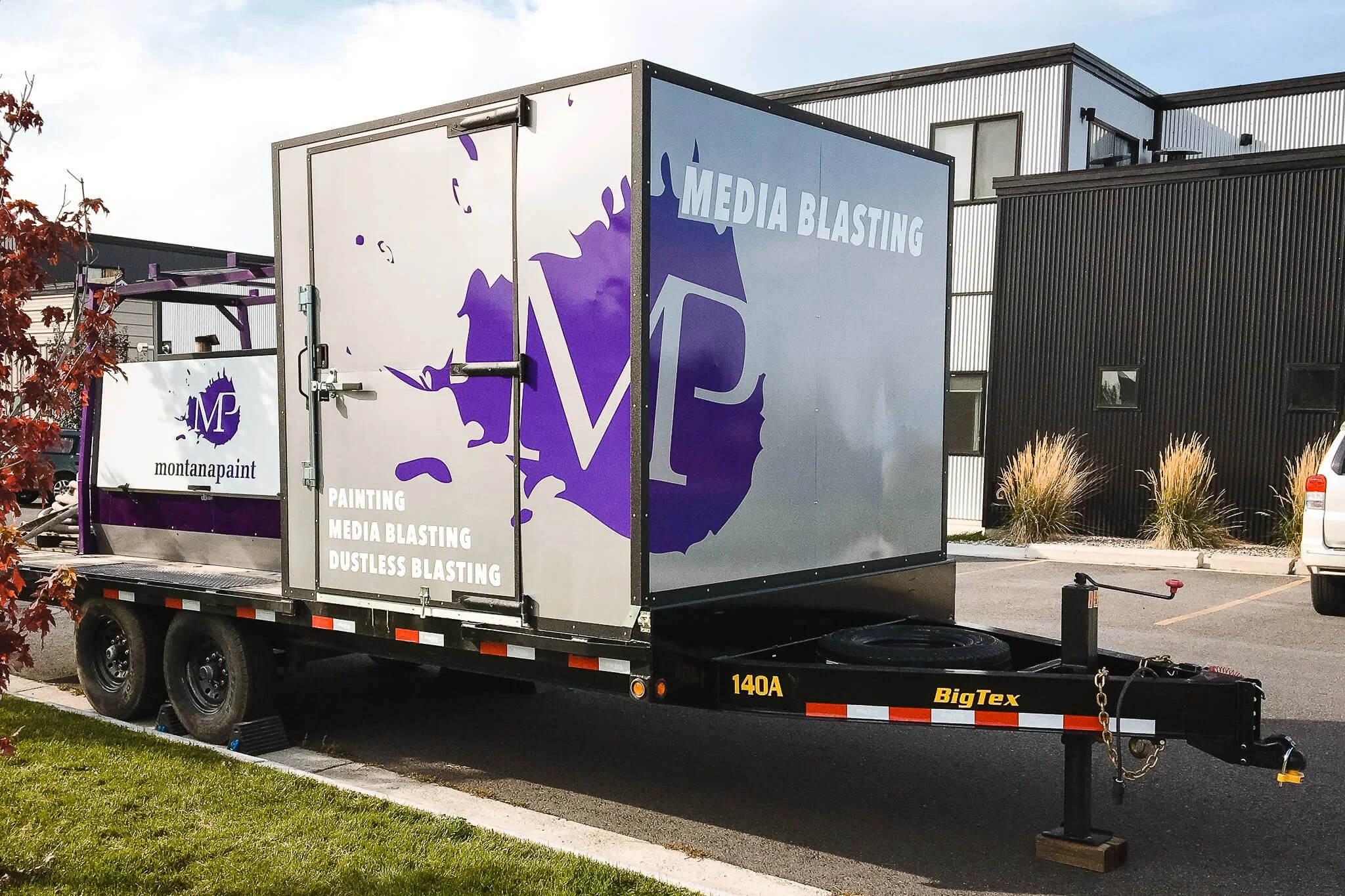 Custom trailer graphics for Montana Paint in Bozeman, Montana, featuring bold purple branding, a large “MP” logo, and listed services like painting and dustless blasting.