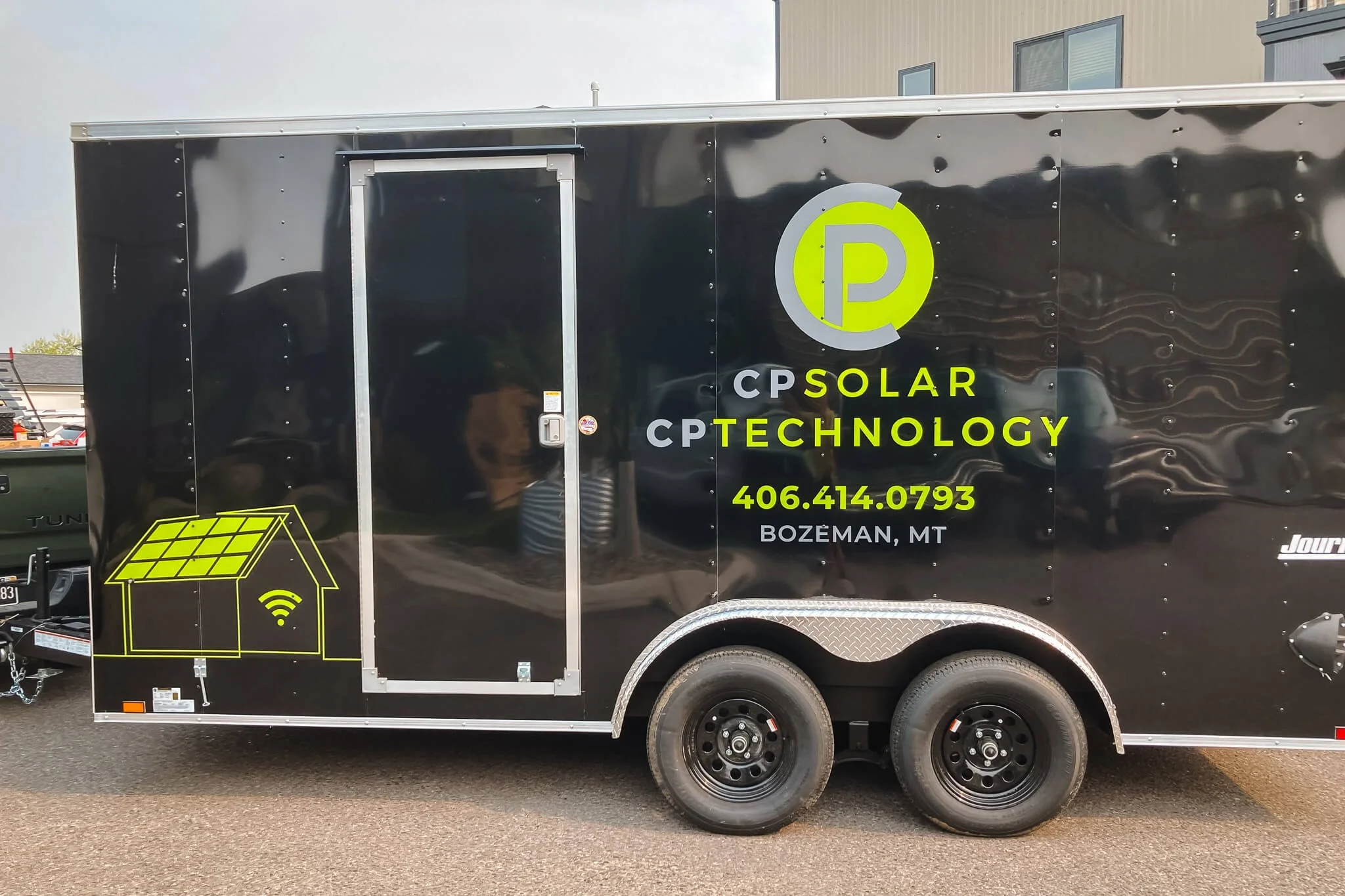 CP Solar CP Technology trailer wrap design in Bozeman, Montana, with neon green and gray solar iconography, emphasizing modern solar and tech services with contact info on a black trailer. 