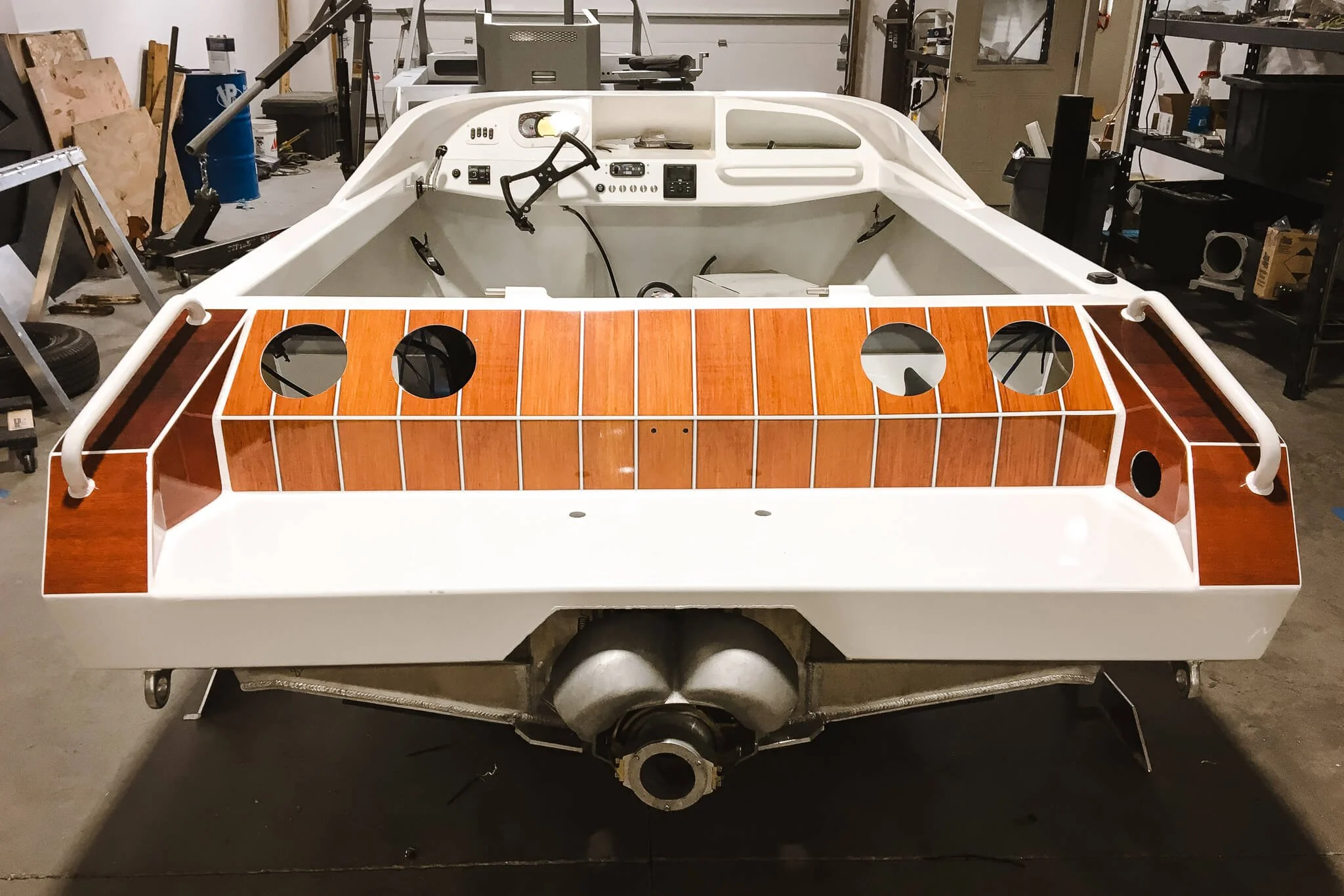 Rear view of a jet boat wrapped in warm-toned woodgrain custom vinyl wrap with white accents and visible inboard motor, photographed in Bozeman, MT.
