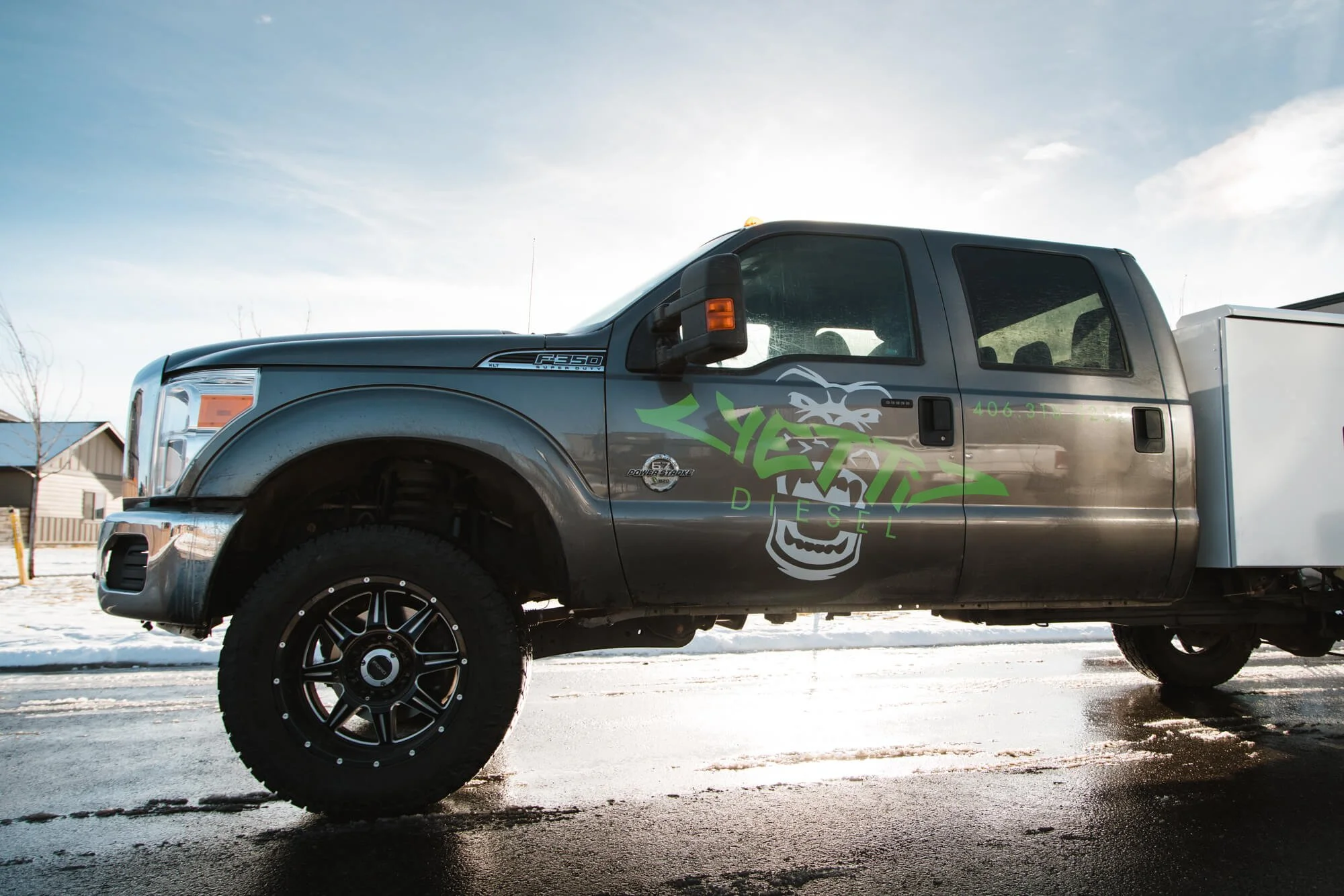 Partial vehicle wrap on a lifted gray F-250 truck displaying a high-impact “YETTI Diesel” logo in white and neon green for a bold brand identity. Installed in Bozeman, Montana.