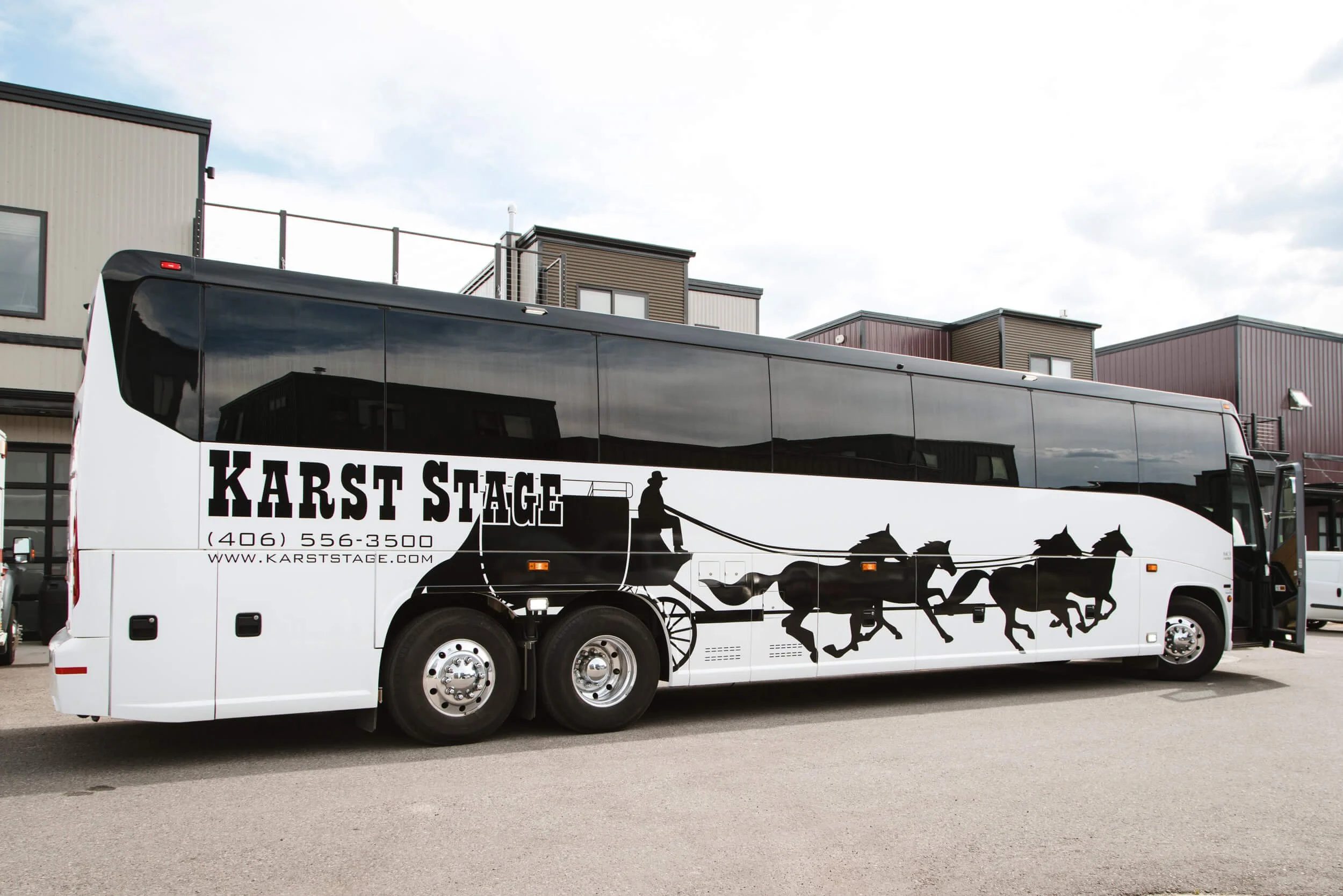 Karst Stage coach bus with gloss black vinyl spot graphics running the length of the sides. Features a large logo with 4 horses pulling a stagecoach