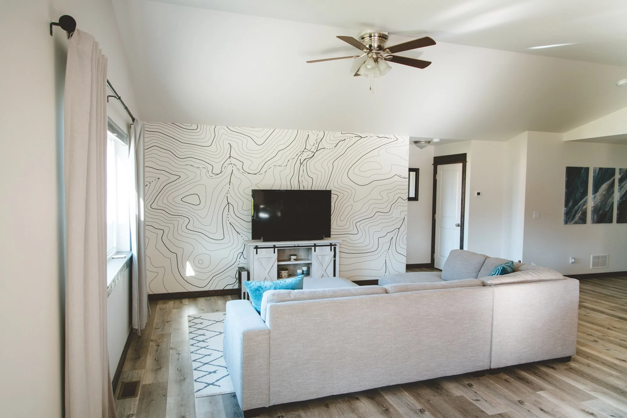 Clean black and white topographic wall wrap installed behind a mounted television in a cozy living room setup at a residential home in Belgrade, MT.
