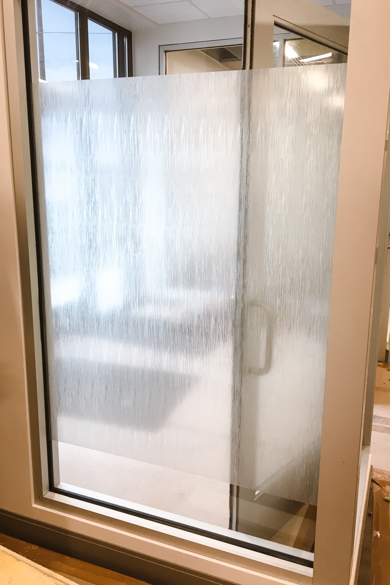Textured frosted window graphics with a rain glass effect applied to interior office glass for a decorative and private visual barrier.