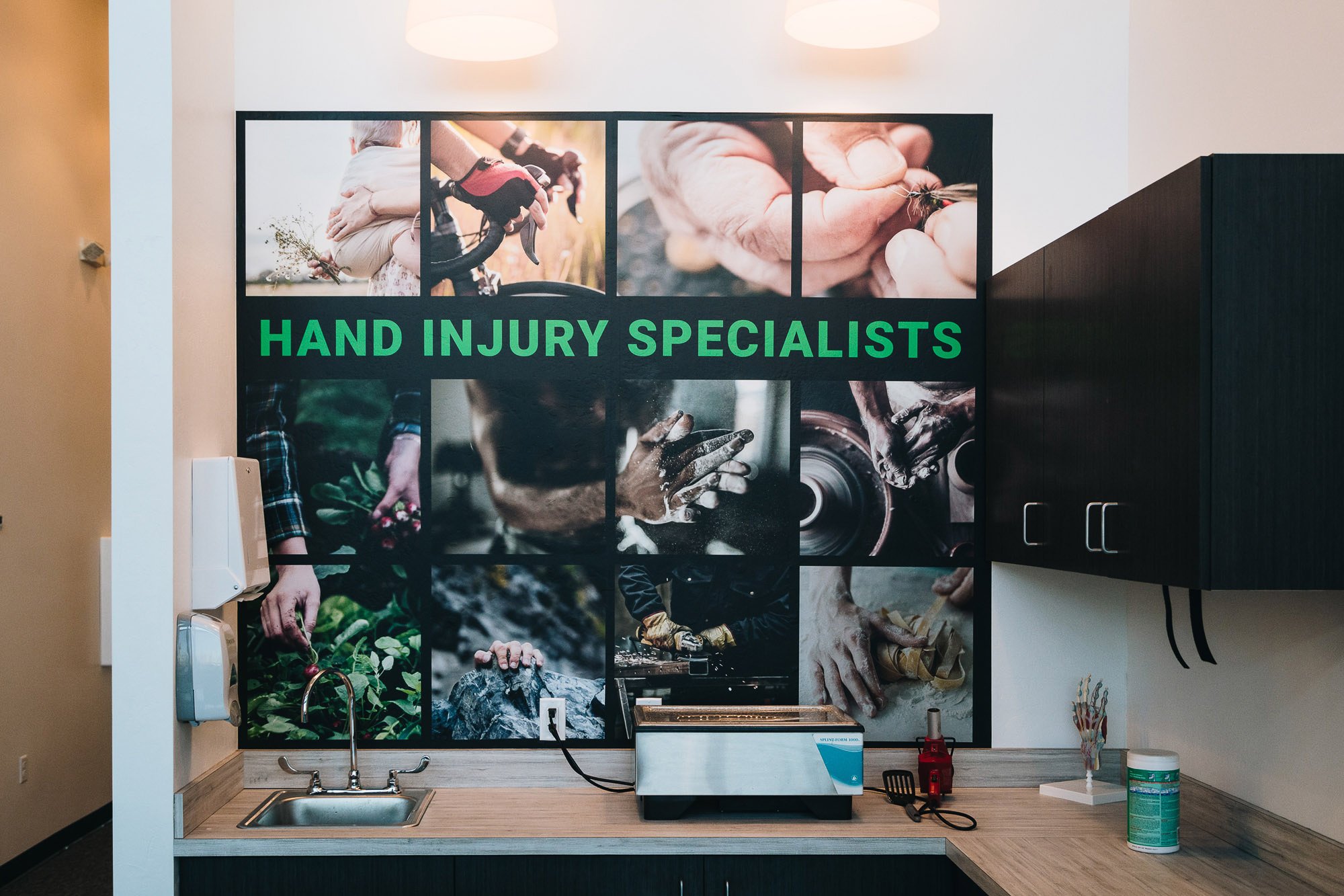 Healthcare wall wrap showcasing hands involved in various activities like pottery, rock climbing, and biking, with green “HAND INJURY SPECIALISTS” text overlayed, designed to emphasize rehabilitation and treatment services. Location: Bozeman, MT.