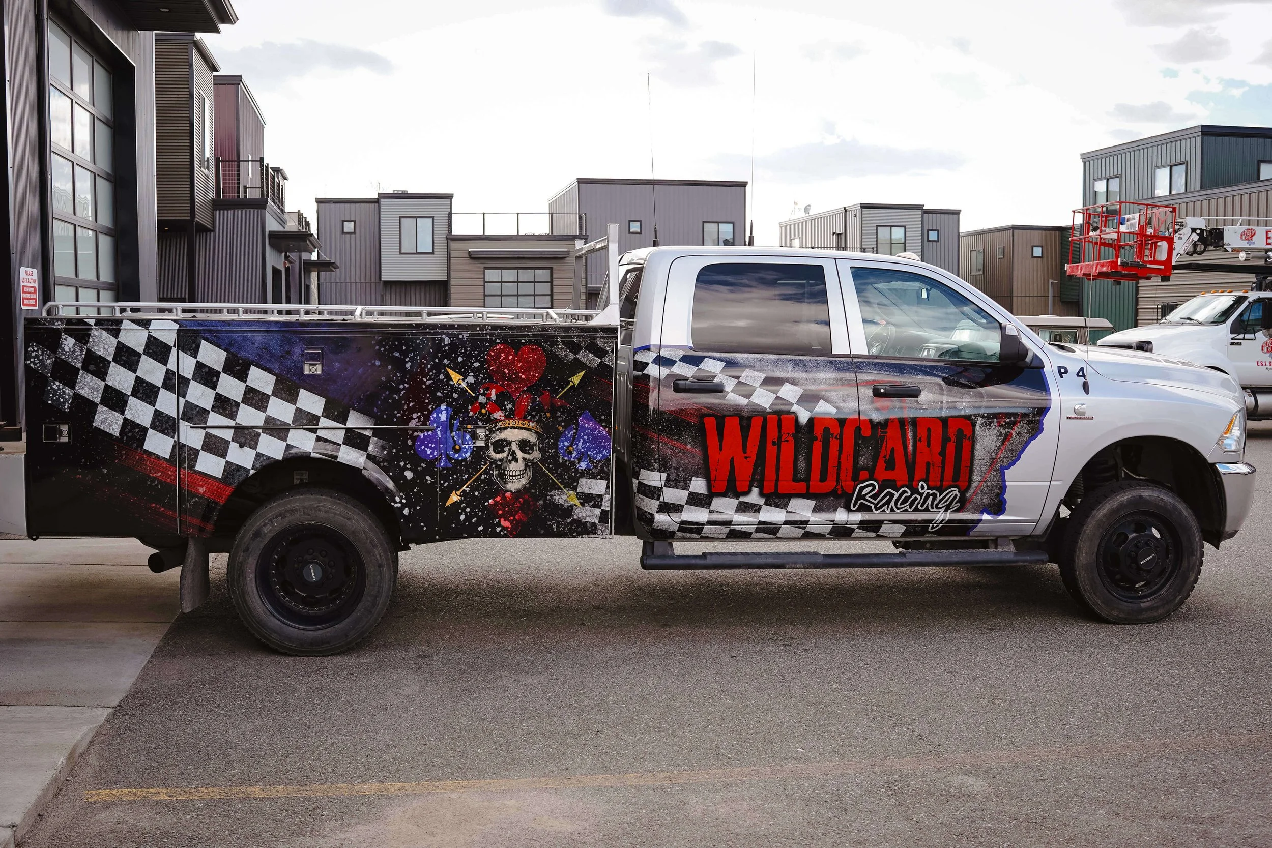 Red, purple and black & white wrap for Wildcard Racing. Features a joker skull on the side of the service bed and a wavy checkboard pattern with colorful distressing