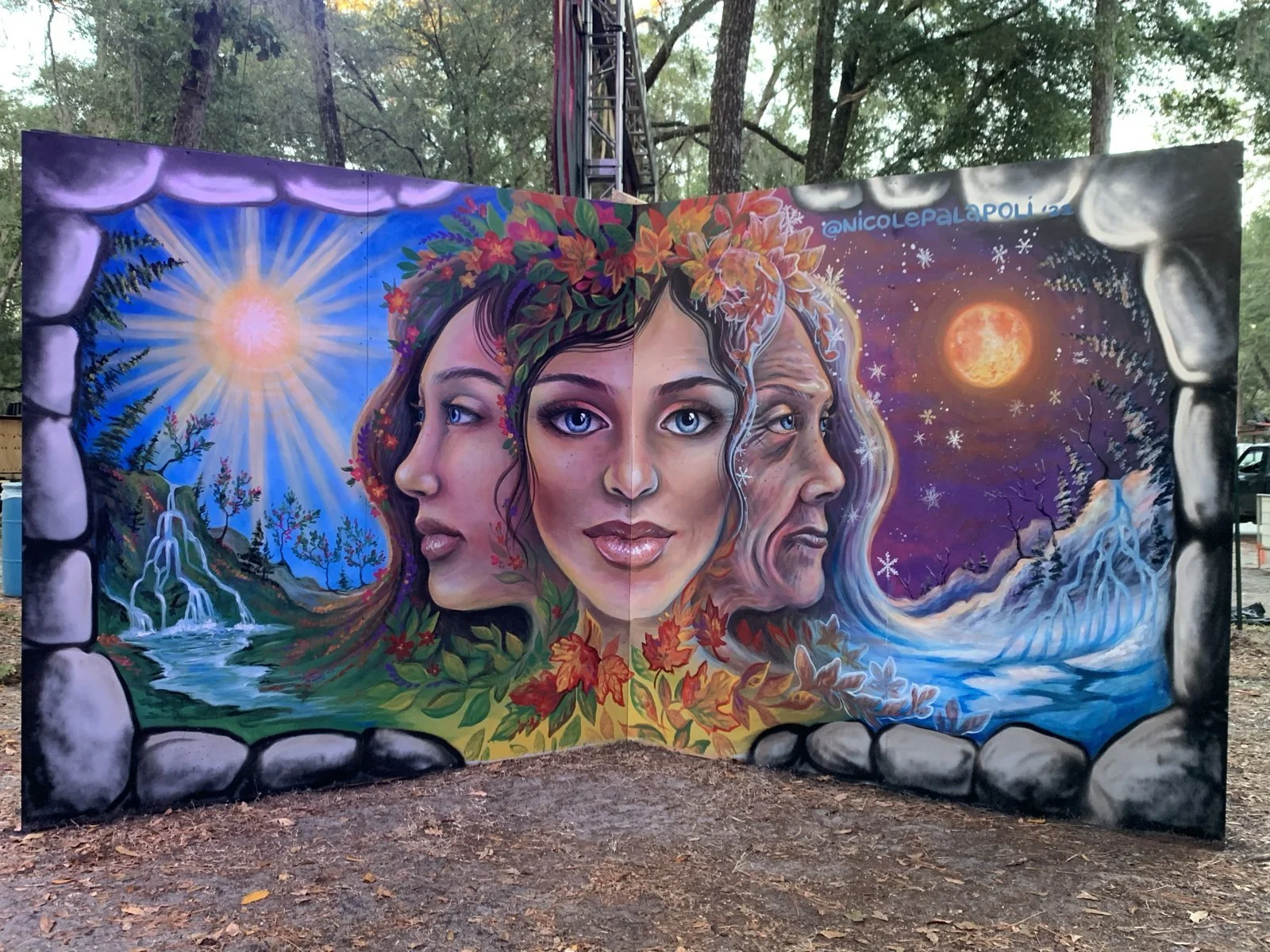 Mural by Nicole Palapoli: three faces with sun and moon, outdoor wall