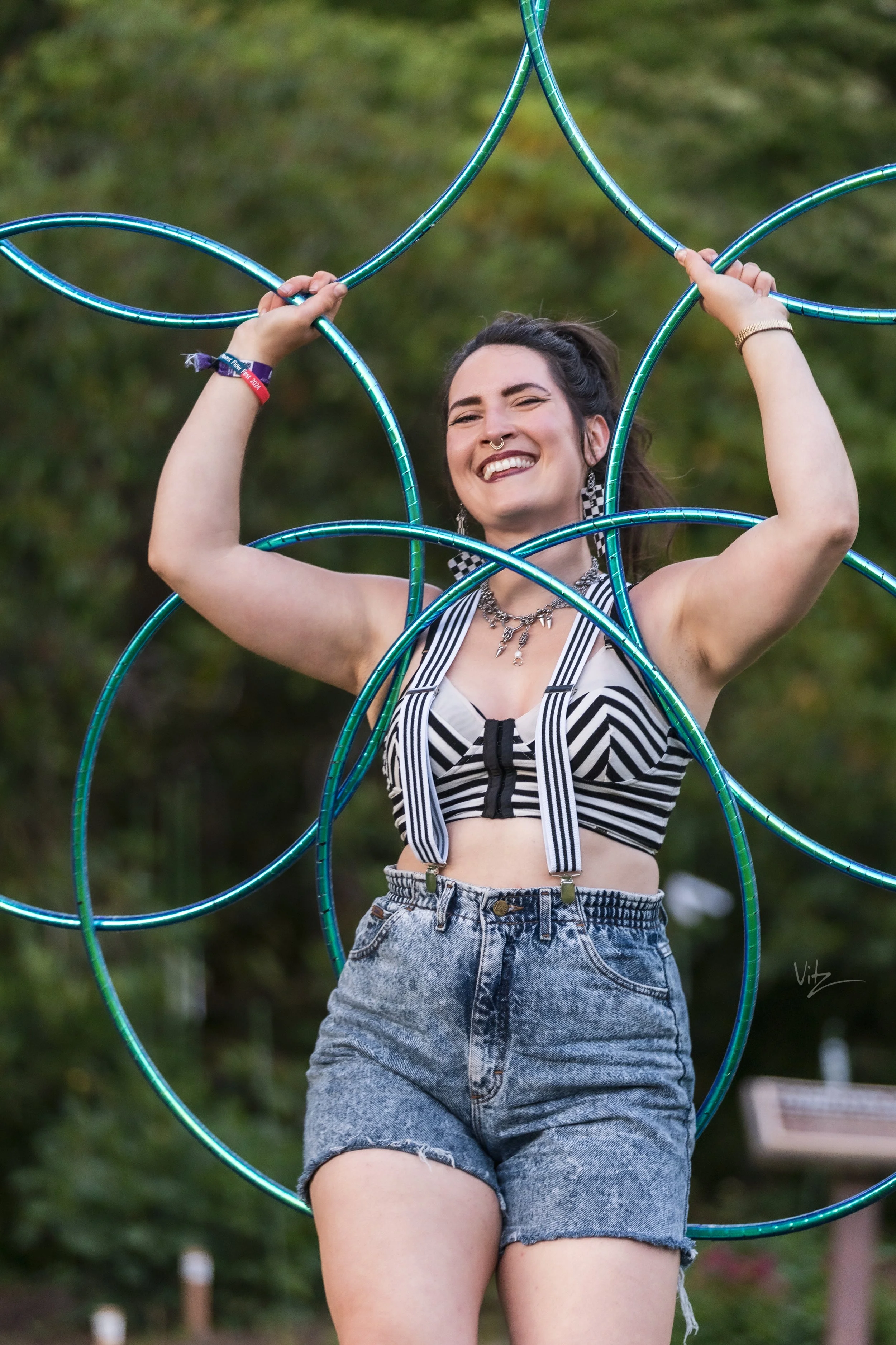 a smiling woman holding hoops in the shape of a mandala .