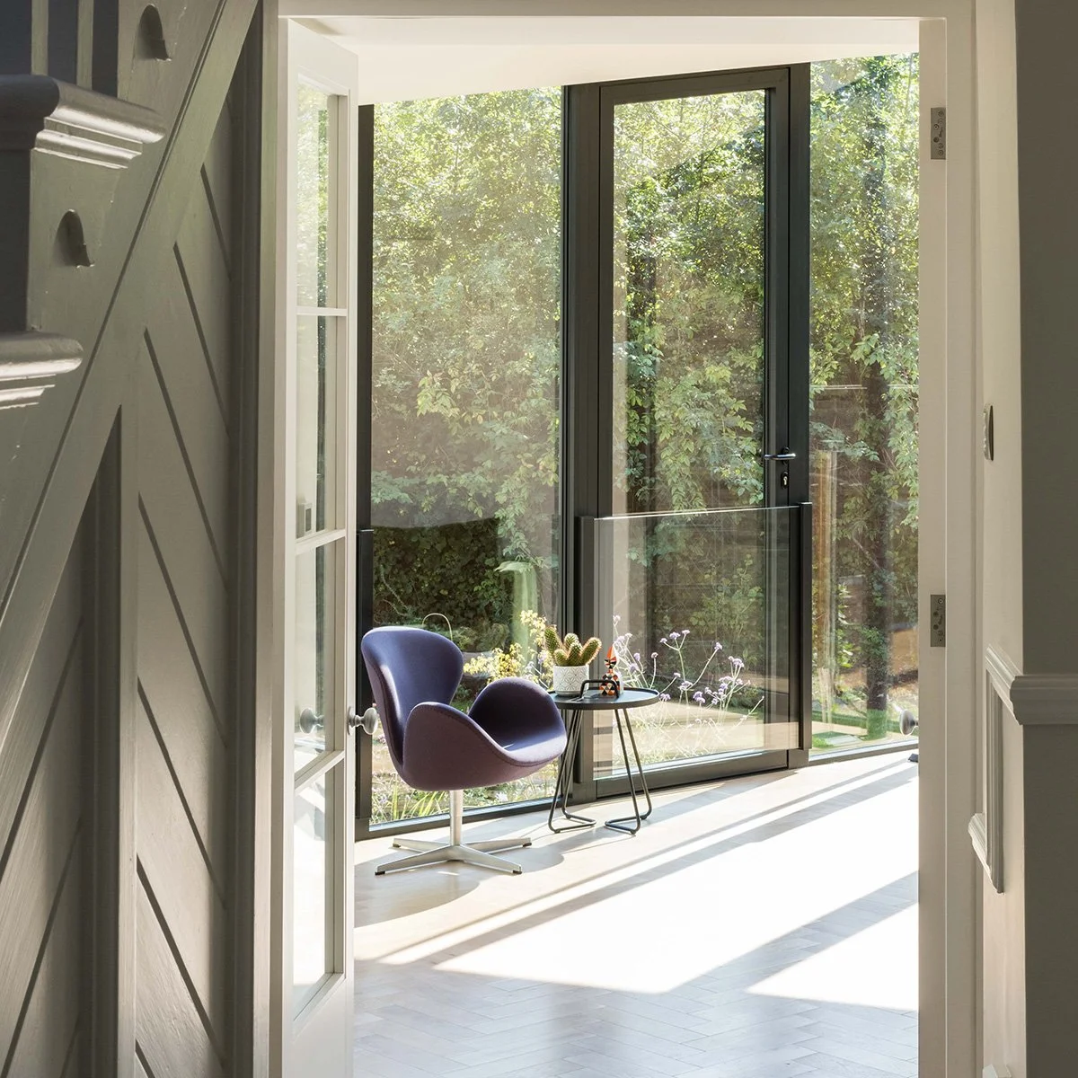 View from the hallway into a light-filled rear extension overlooking the garden and trees at Culverden Road, Balham.