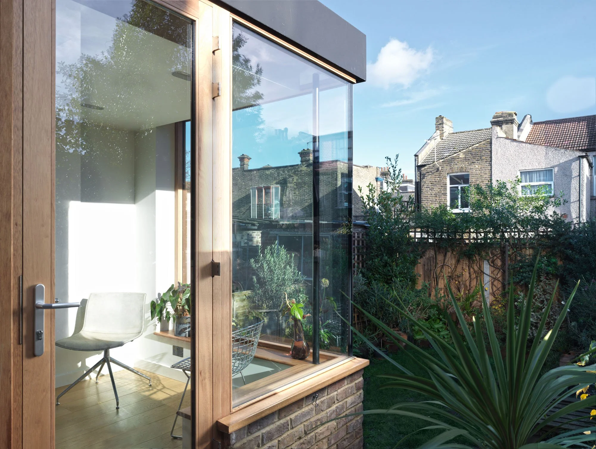 Timber-framed garden room extension at Rensburg Villas with corner glazing and views into the planting.