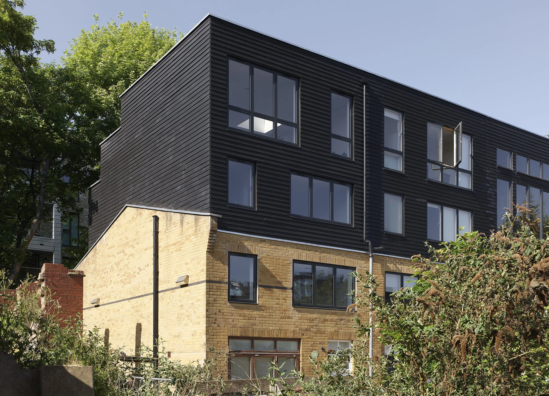 Black-clad roof extension above an existing brick live-work building in London Fields, Hackney by Studio CMA