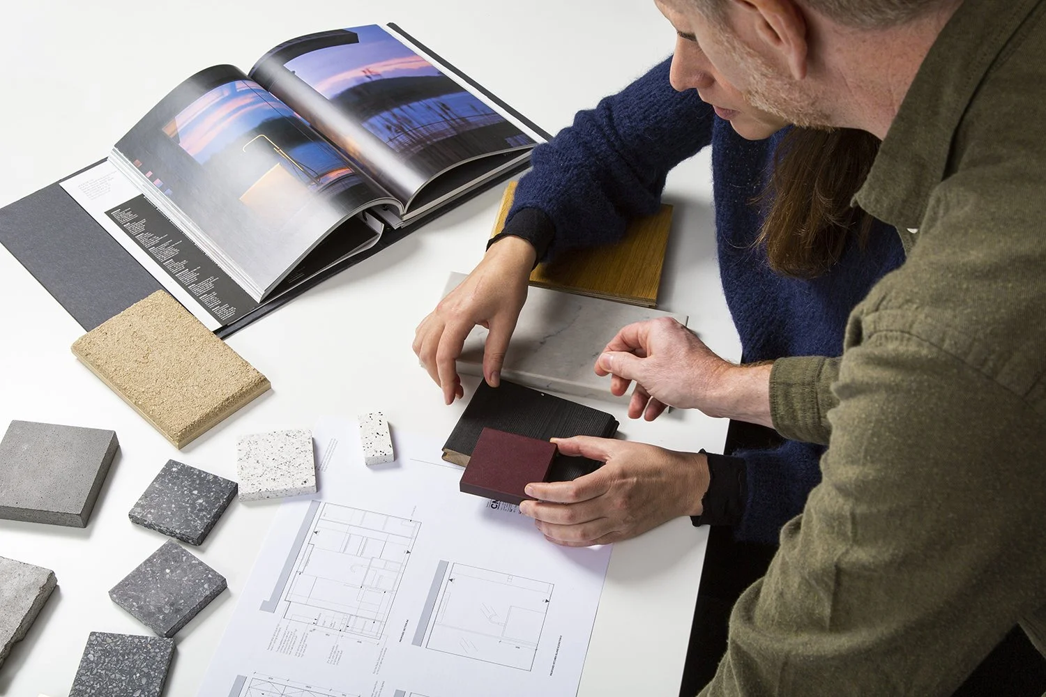Greg and Daniela reviewing materials and architectural layouts at their studio table, selecting finishes for a bespoke home interior.