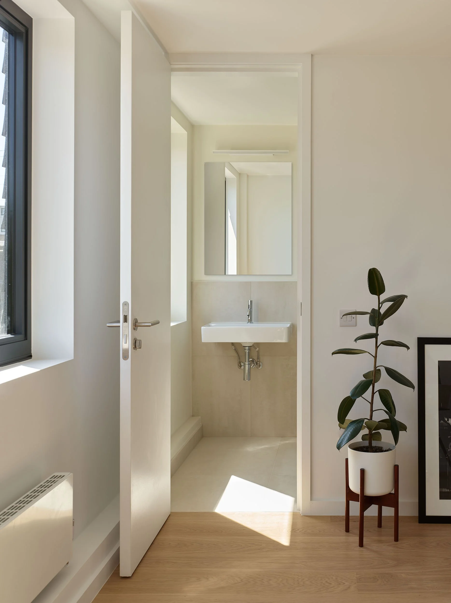 Bathroom within the roof extension, with daylight from a window and a compact layout designed for an upper-floor flat in Hackney.