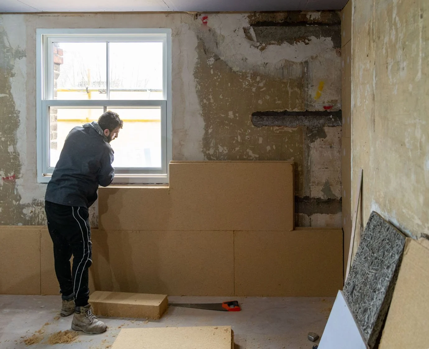 Installer fitting natural wood-fibre internal wall insulation to a flat within a semi-detached Victorian building in Crouch End, London.