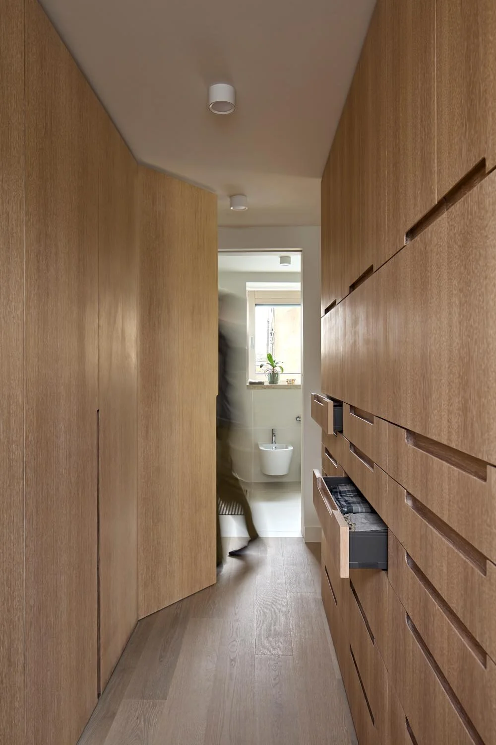 Bespoke oak dressing corridor with integrated storage in a Lower Clapton loft suite by Studio CMA