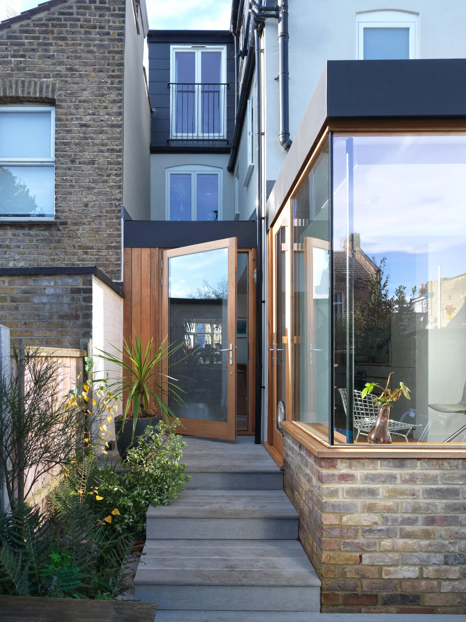 Timber steps and deck connecting a glazed Victorian rear extension with the lower garden