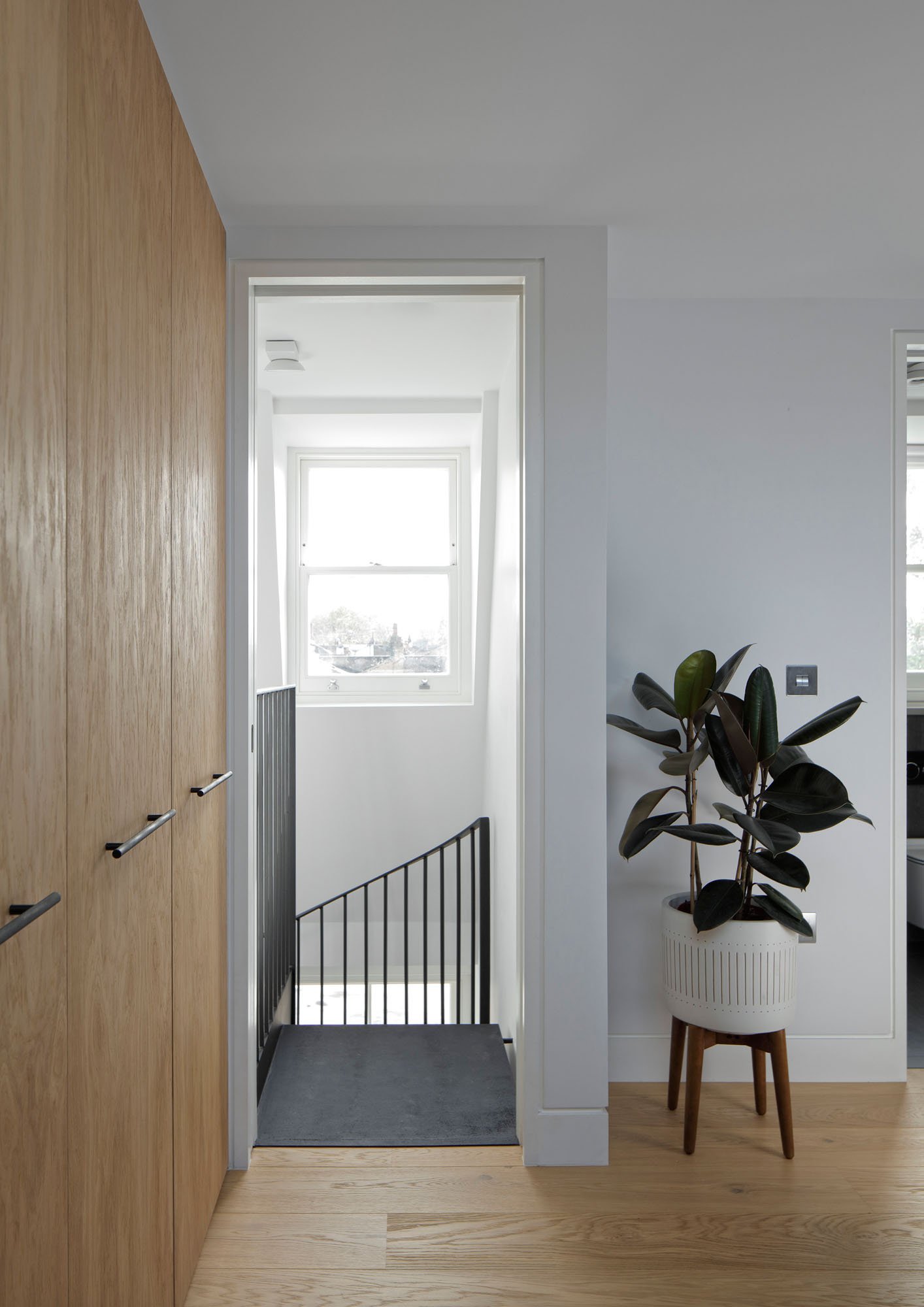 Prebend Street loft landing with bespoke oak storage, stair opening and borrowed daylight in an Islington period home.