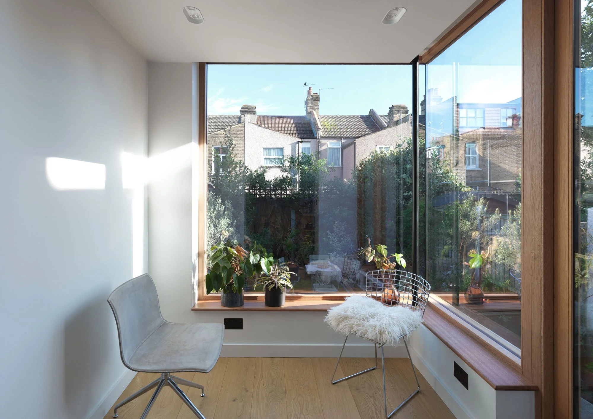 Landscape view of a glazed garden room filled with morning light and overlooking neighbouring rooftops