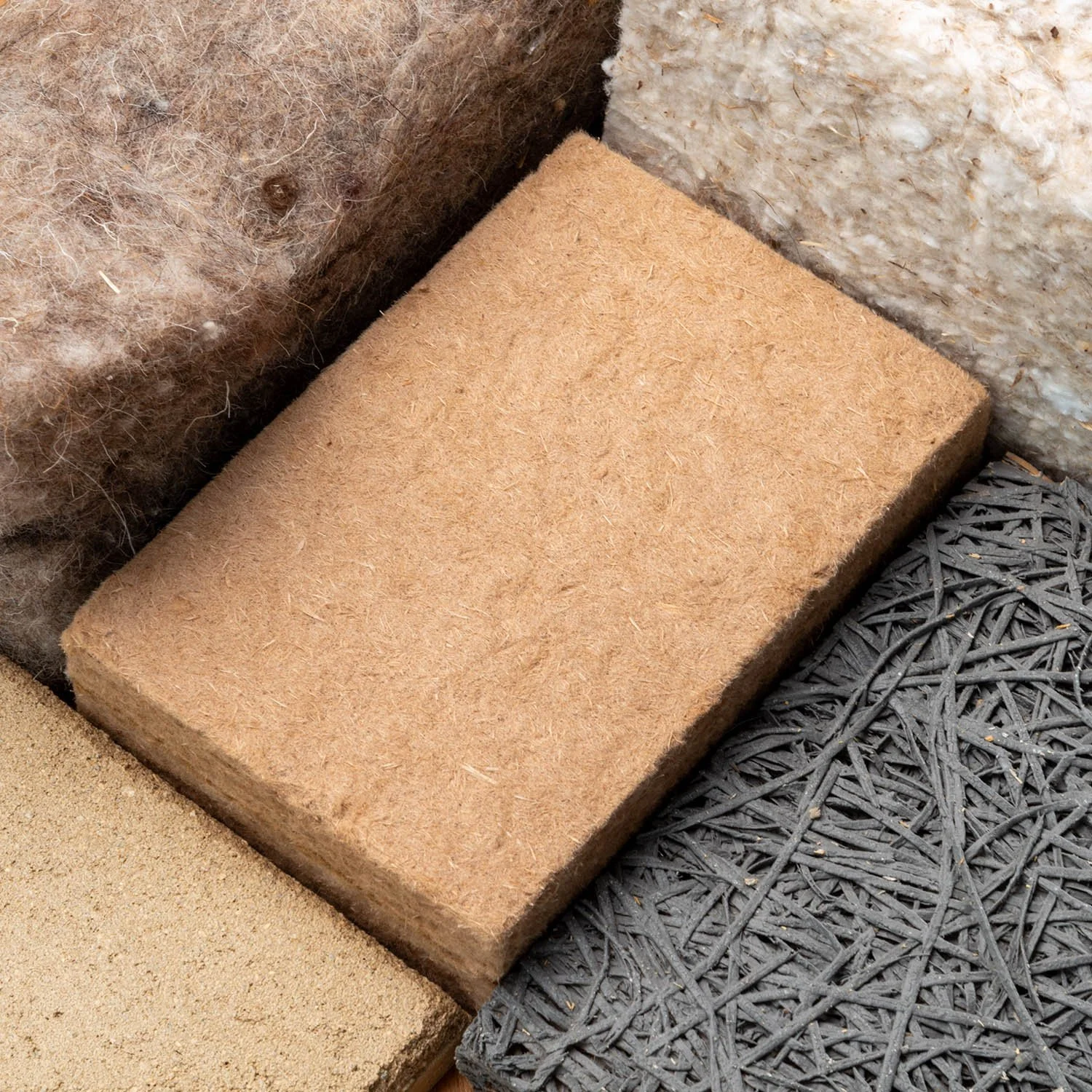Close-up of natural insulation materials including wood fibre, hemp, cork, and recycled fibres for moisture-safe retrofits.