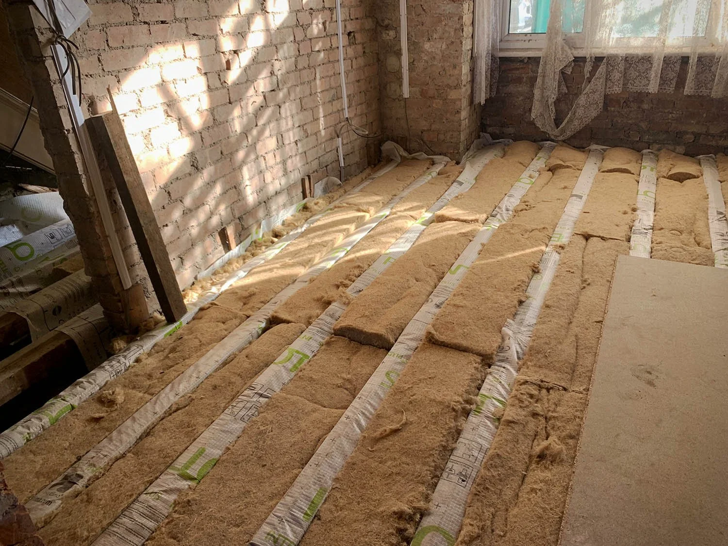 Suspended timber floor insulation being installed between joists in a North London Victorian terrace