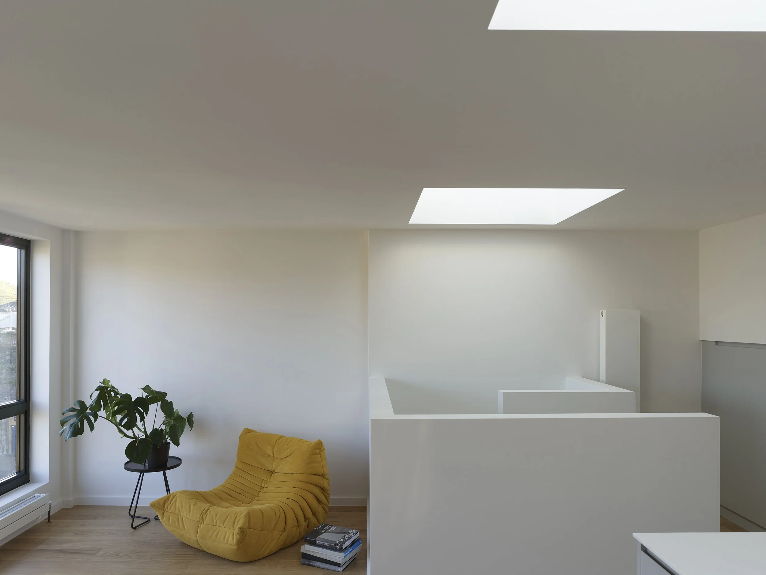 Top-floor living space within the roof extension, with rooflights bringing daylight into a compact upper-level flat in Hackney.