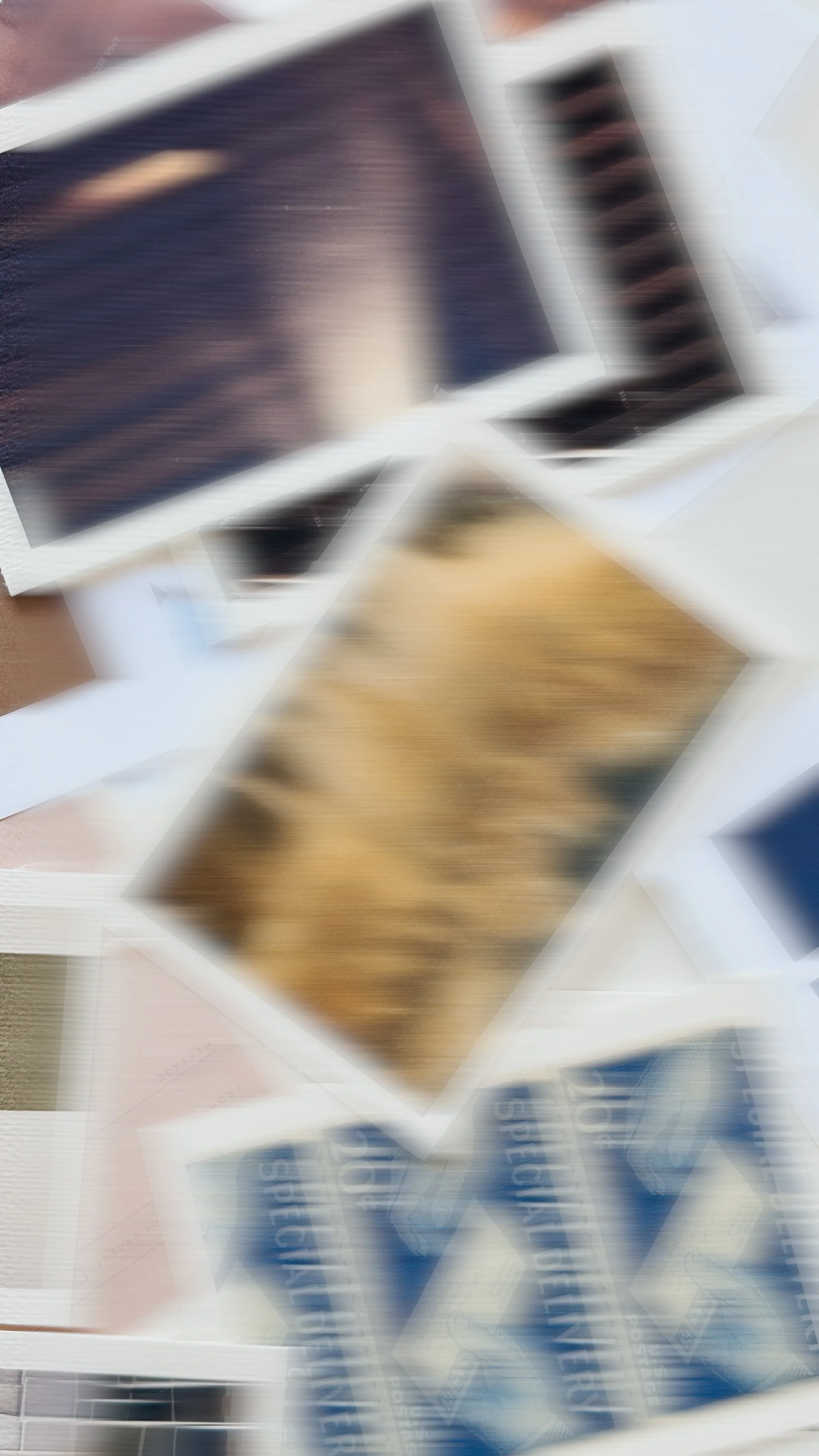 Blurred image of various printed documents or posters, some with text and barcode, overlapping on a surface.