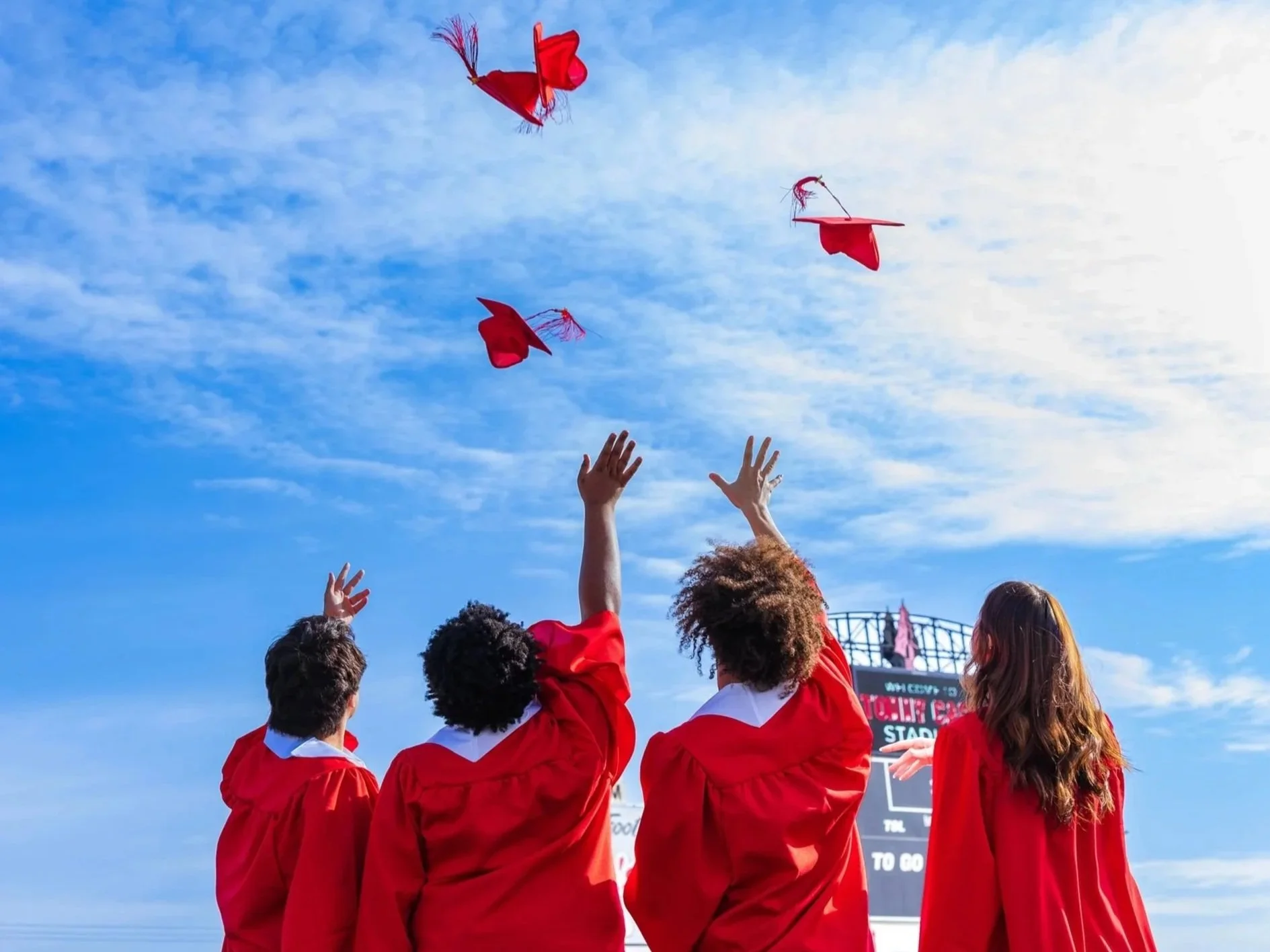 Close-up of a graduation cap on a student's head during a graduation ceremony, with people in academic regalia in the background.