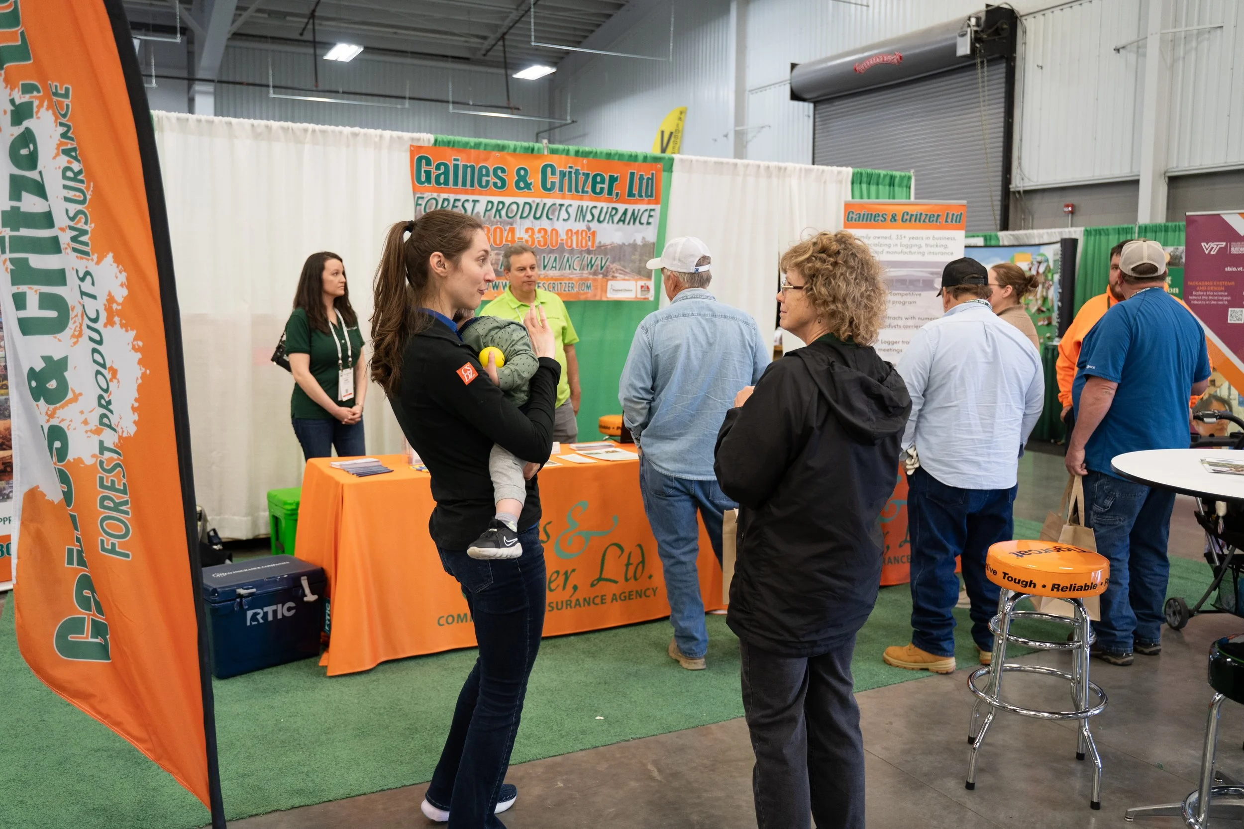 Trade show booth for Gaines & Critzer, Ltd, an insurance company, with several visitors engaging with representatives in an indoor exhibition space.