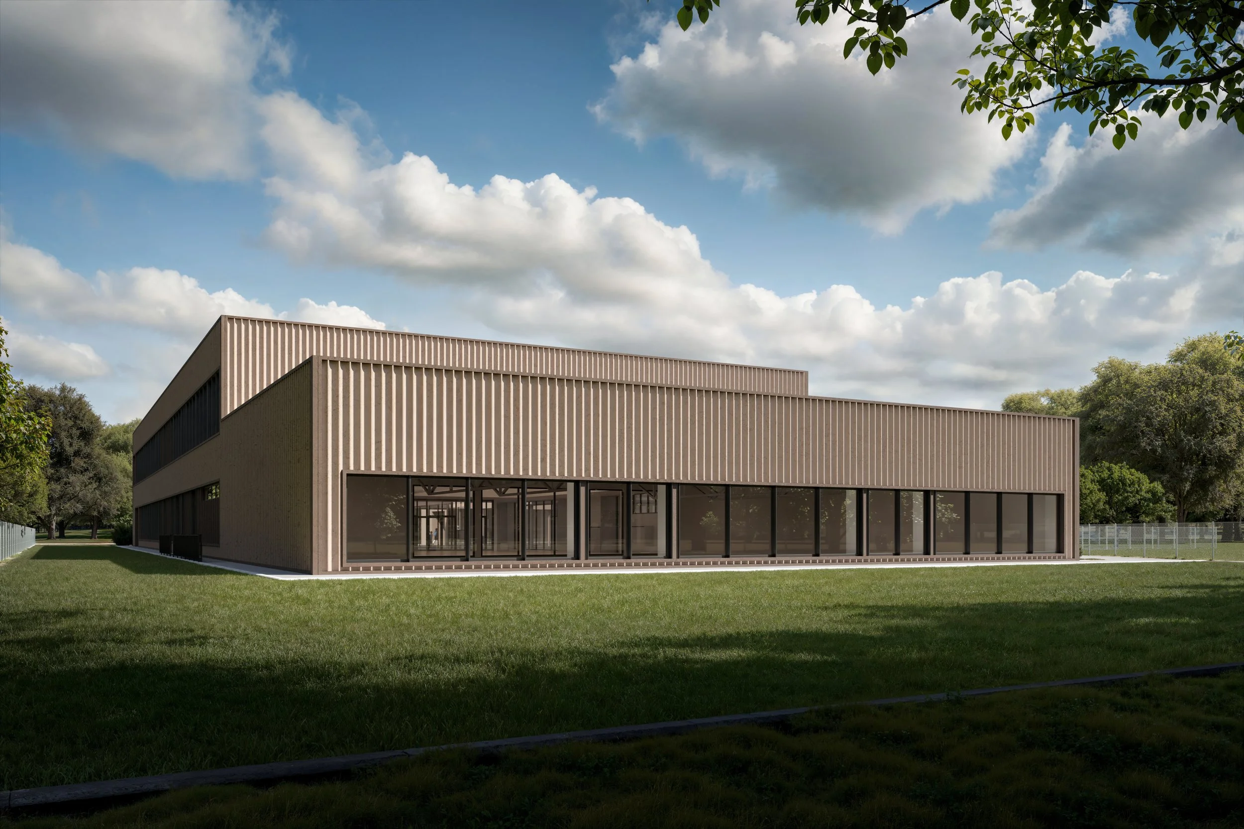 Modern two-story building with wooden exterior and large glass windows, surrounded by green grass and trees, under a partly cloudy sky.