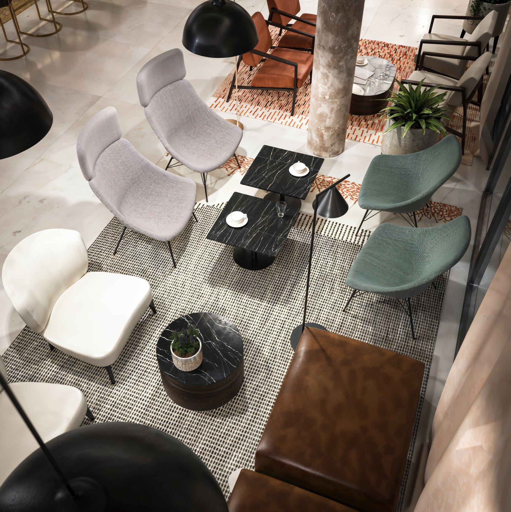 A top-down view of a modern lounge area with various chairs, marble-topped tables, black hanging lamps, a large potted plant, and a patterned rug.