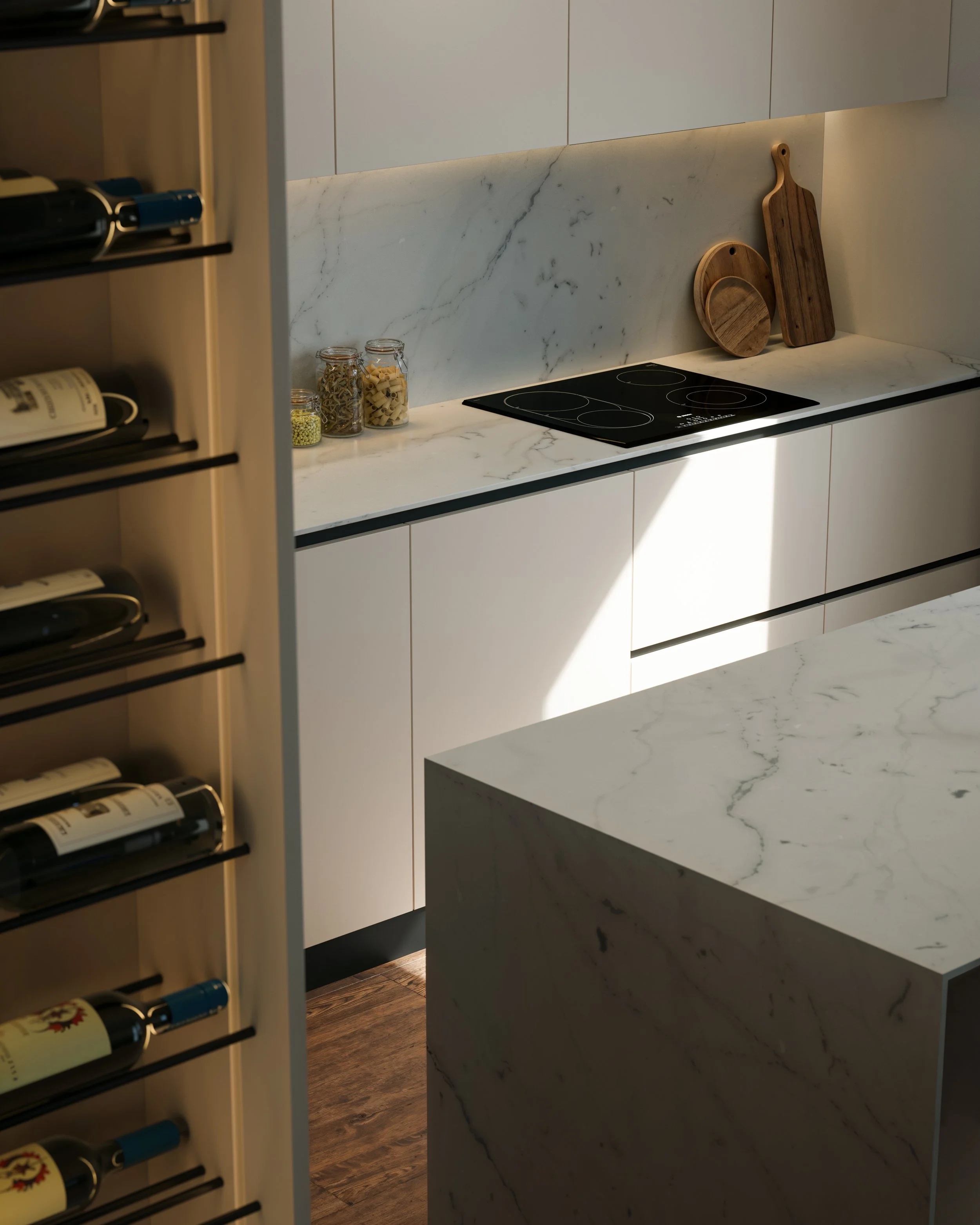 Modern kitchen with white cabinets, marble countertops, and a black electric cooktop. Wooden cutting boards and jars of pasta and grains are on the counter. Wine bottles are visible on a nearby wine rack.