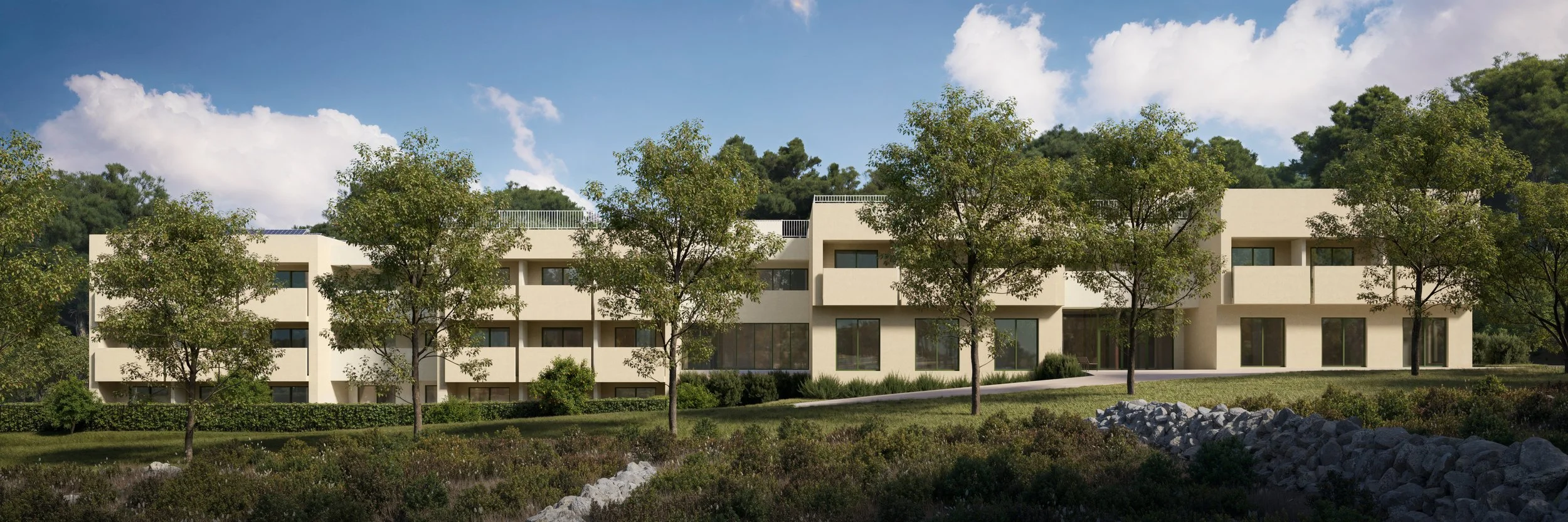 Modern beige residential building with multiple large windows, surrounded by green trees and landscape, under a blue sky with clouds.