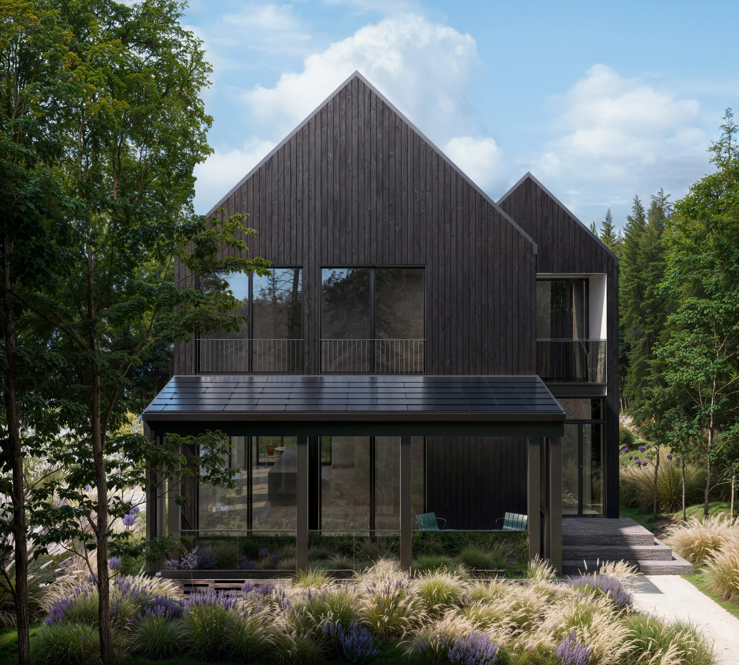 A modern black house with large windows and a sloped roof, surrounded by lush greenery and landscaped garden with purple and white ornamental grasses, and a pathway leading to the entrance.