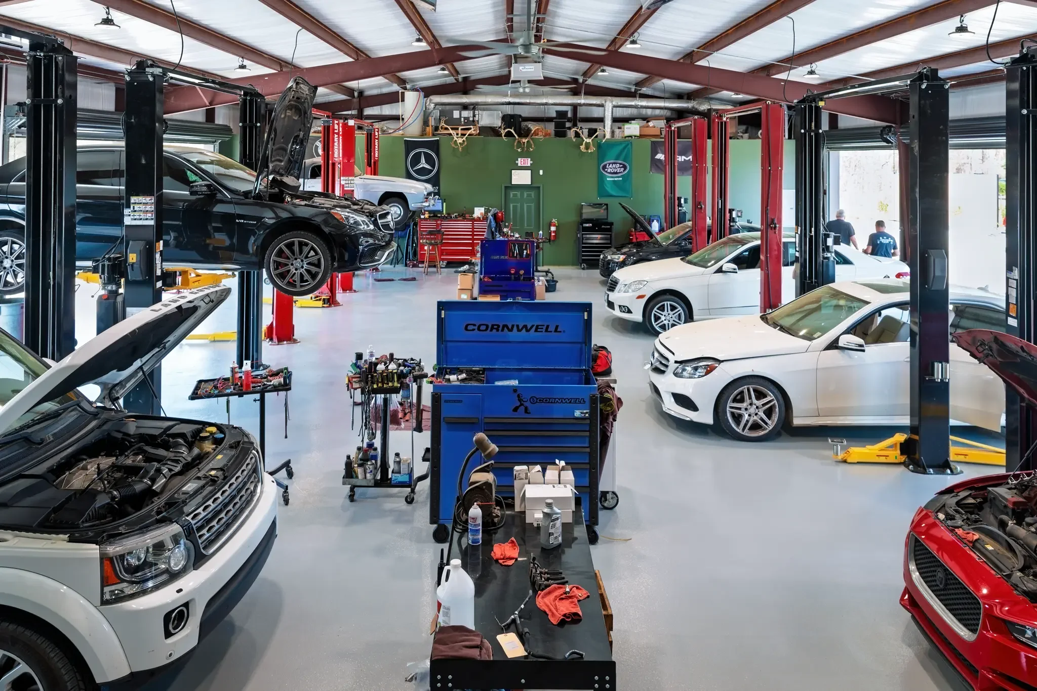 Inside European Auto Repair in Ridgeland, MS — multiple service bays with Mercedes-Benz and Land Rover vehicles being serviced, professional lifts, Cornwell tool chests, and certified technicians at work on Ford Street off Highway 51
