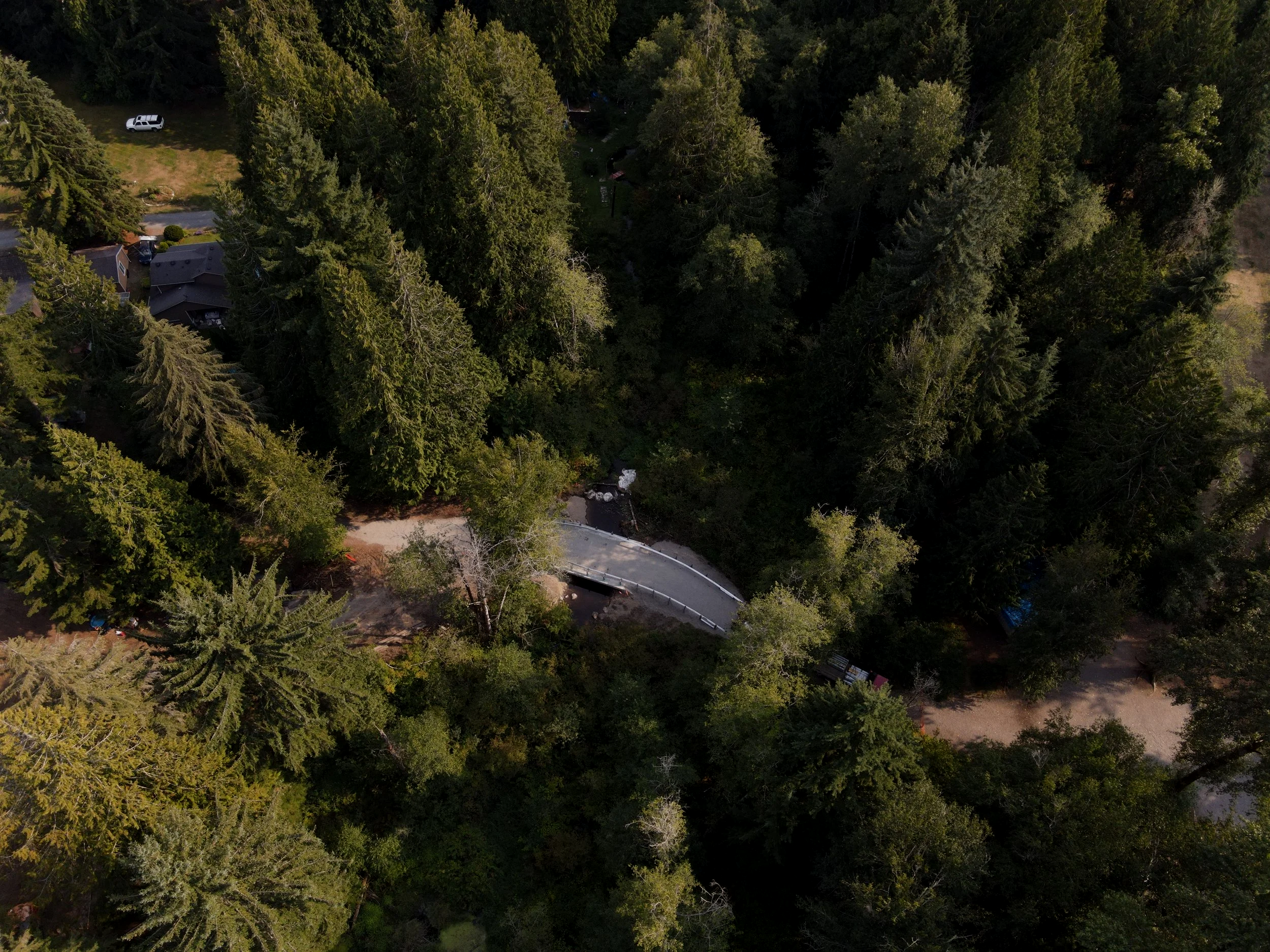 An aerial view of a road with a bridge in the woods.