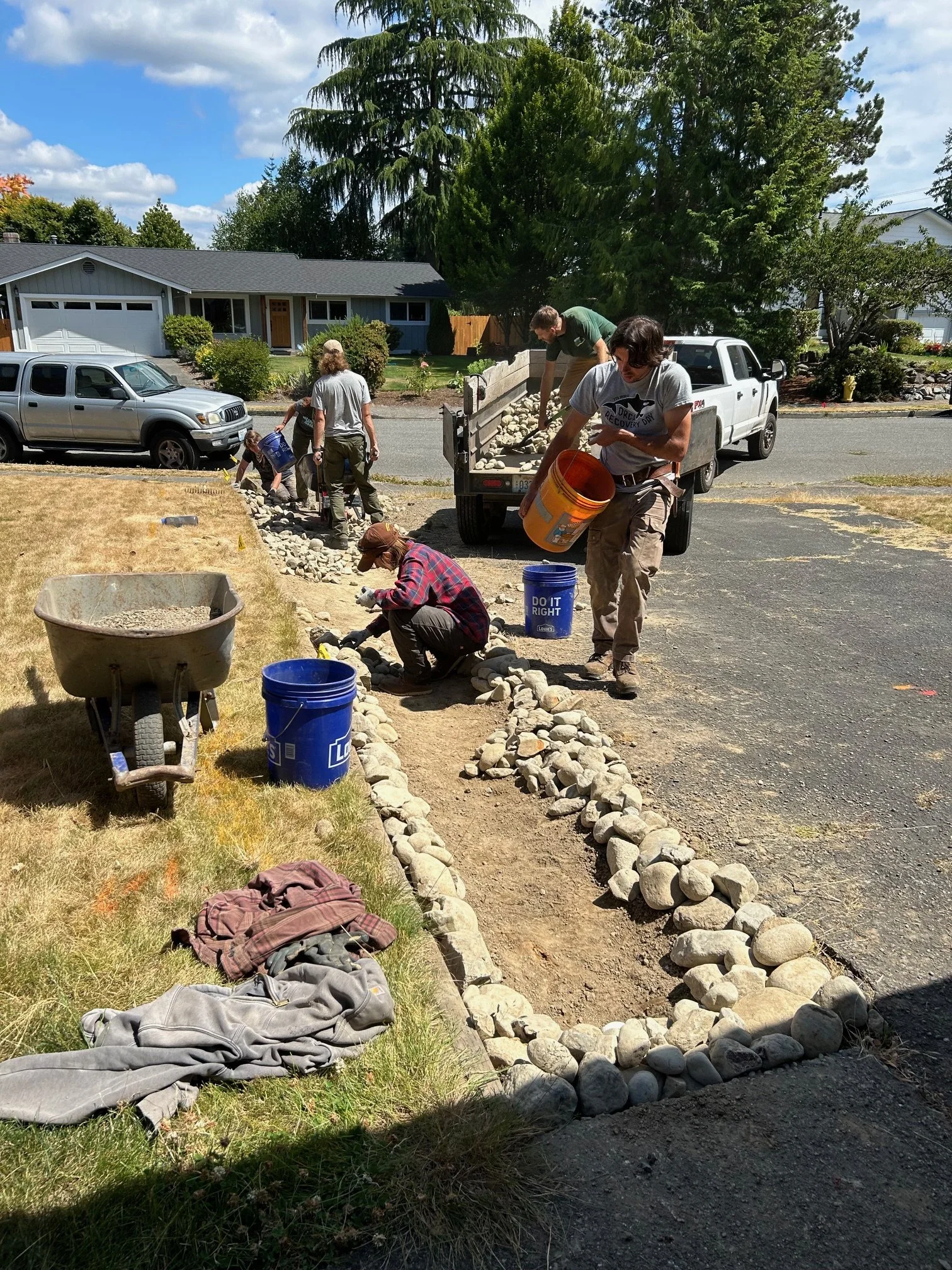 People pour river rock along a driveway