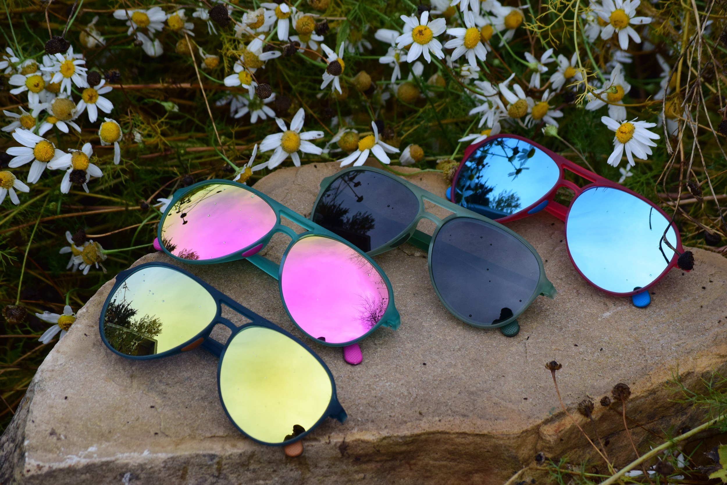 Four pairs of Das Optics Deputy polarized aviators showing gold, pink, smoke, and blue mirror lenses with colored temple tips