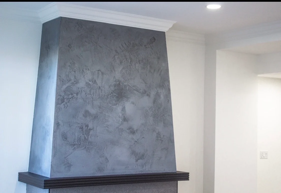 Interior view of a house fireplace with a textured gray finish and white crown molding ceiling.