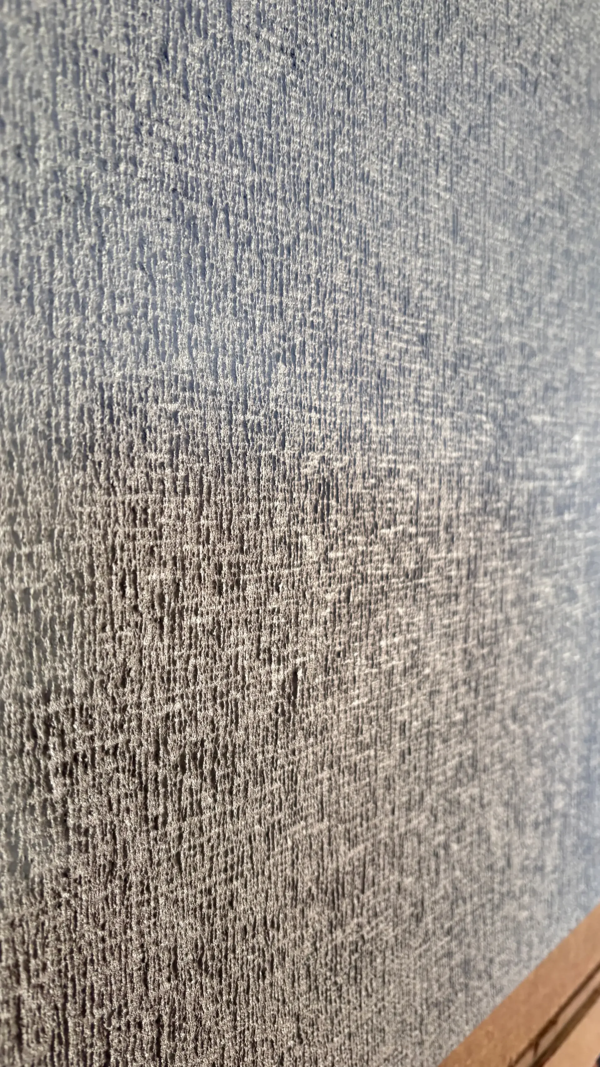 Close-up of a textured, gray wall surface with visible rough grain.
