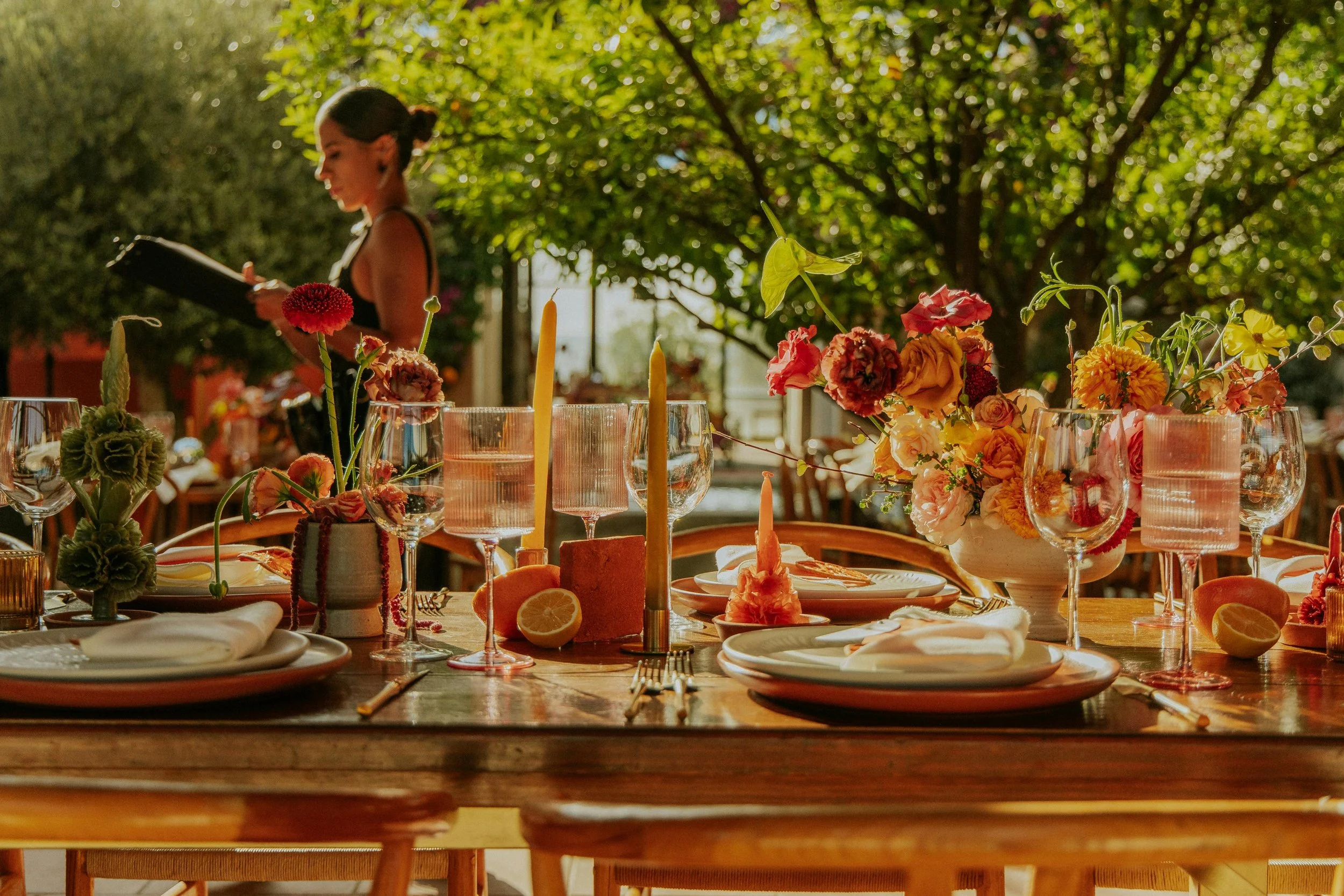 An open-air table layered with flowers, candlelight, and considered place settings