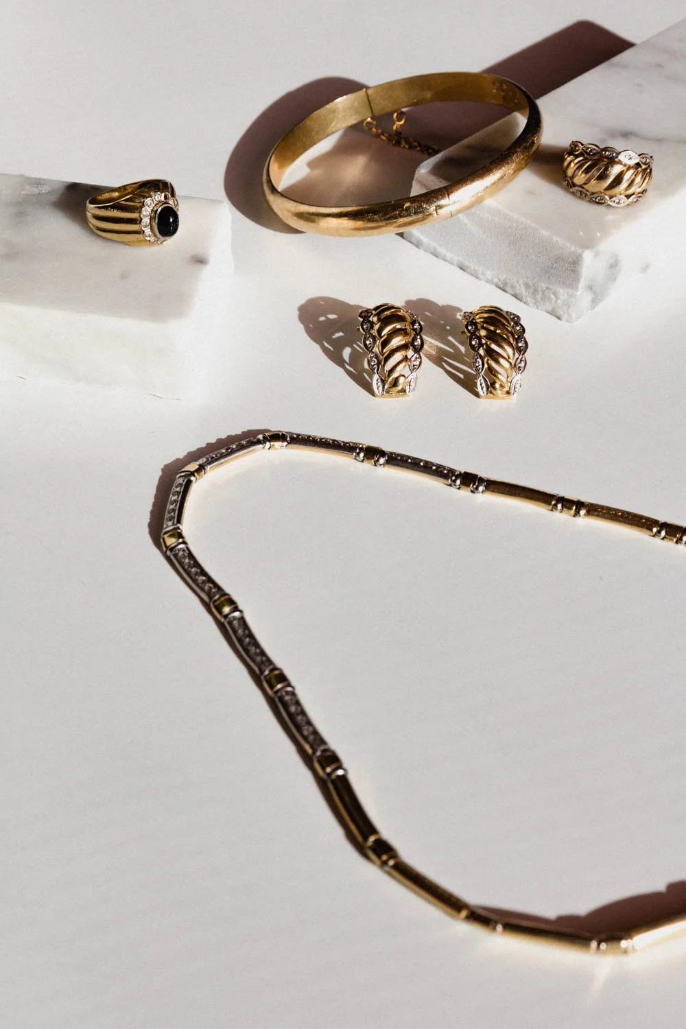 set of gold jewellery on a piece of marble with a white background